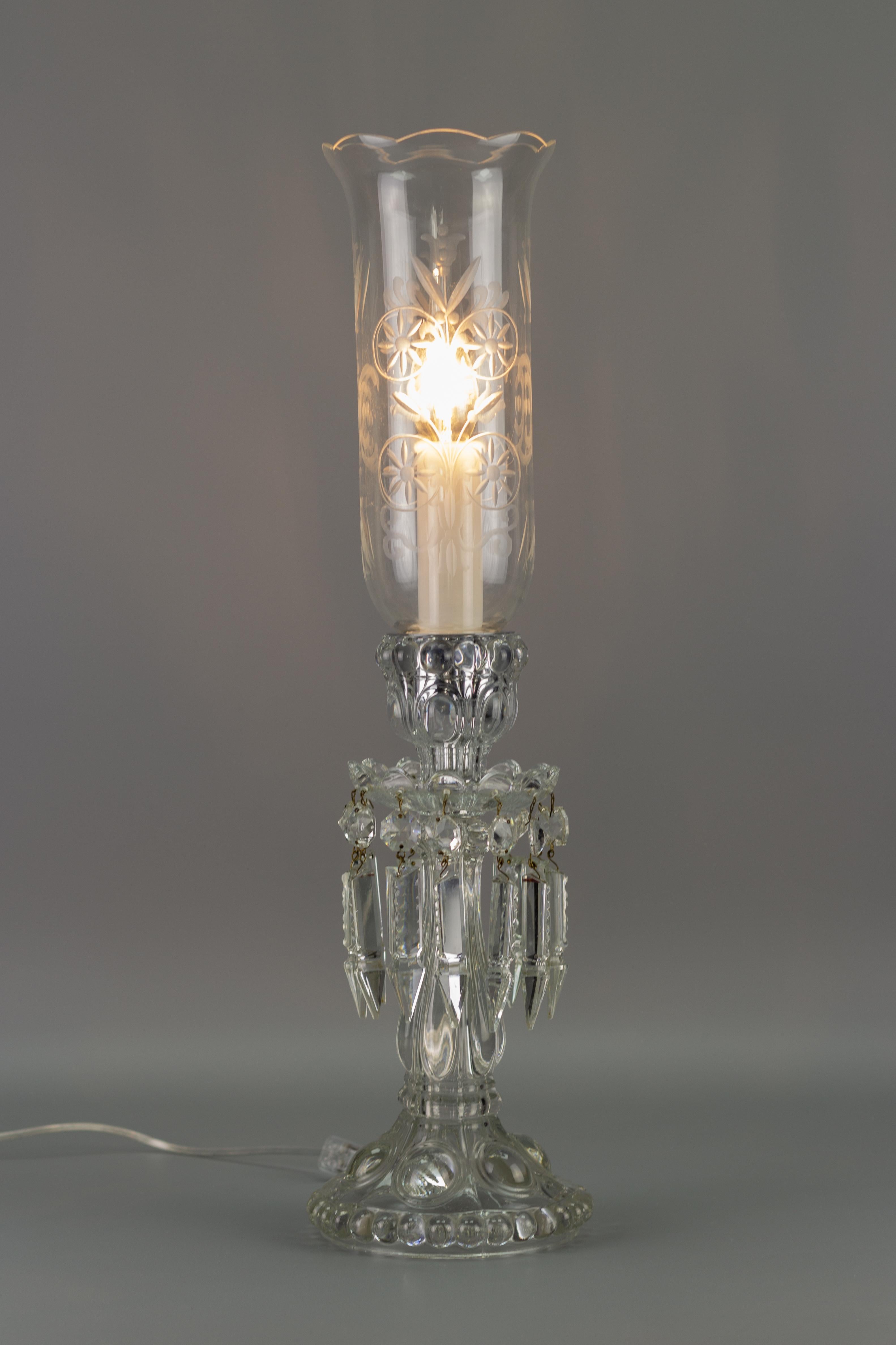 This wonderful vintage glass table lamp features a floral pattern cut into the beautifully shaped glass shade. The glass lamp is decorated with zipper cut crystal prisms. 
One socket for an E14 size light bulb.
Dimensions: height: 59 cm / 23.22