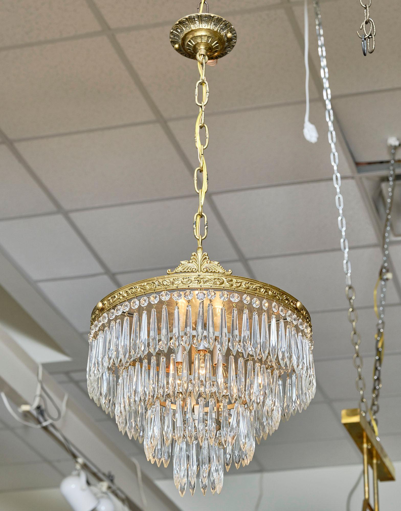 Chandelier from France made of four tiers of cut crystal pendants hanging from an embossed brass structure in the Louis XVI style. This piece has been newly wired to fit US standards.