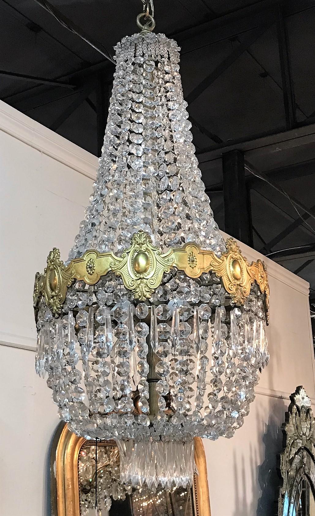 Fabulous French crystal and gilt bronze basket-form chandelier. The embossed gilt bronze band separates long beautiful strands of cut crystal beads with flower head accents. 

Made in France, circa 1900.