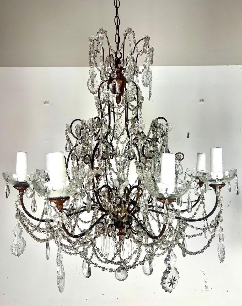 Lampadario francese a 8 luci in cristallo con cristalli incisi a stella e ghirlande di perline di maccheroni, che conferiscono un aspetto unico e opulento.  L'uso di un terminale di cristallo al centro, insieme a bobeches in legno dorato, aggiunge