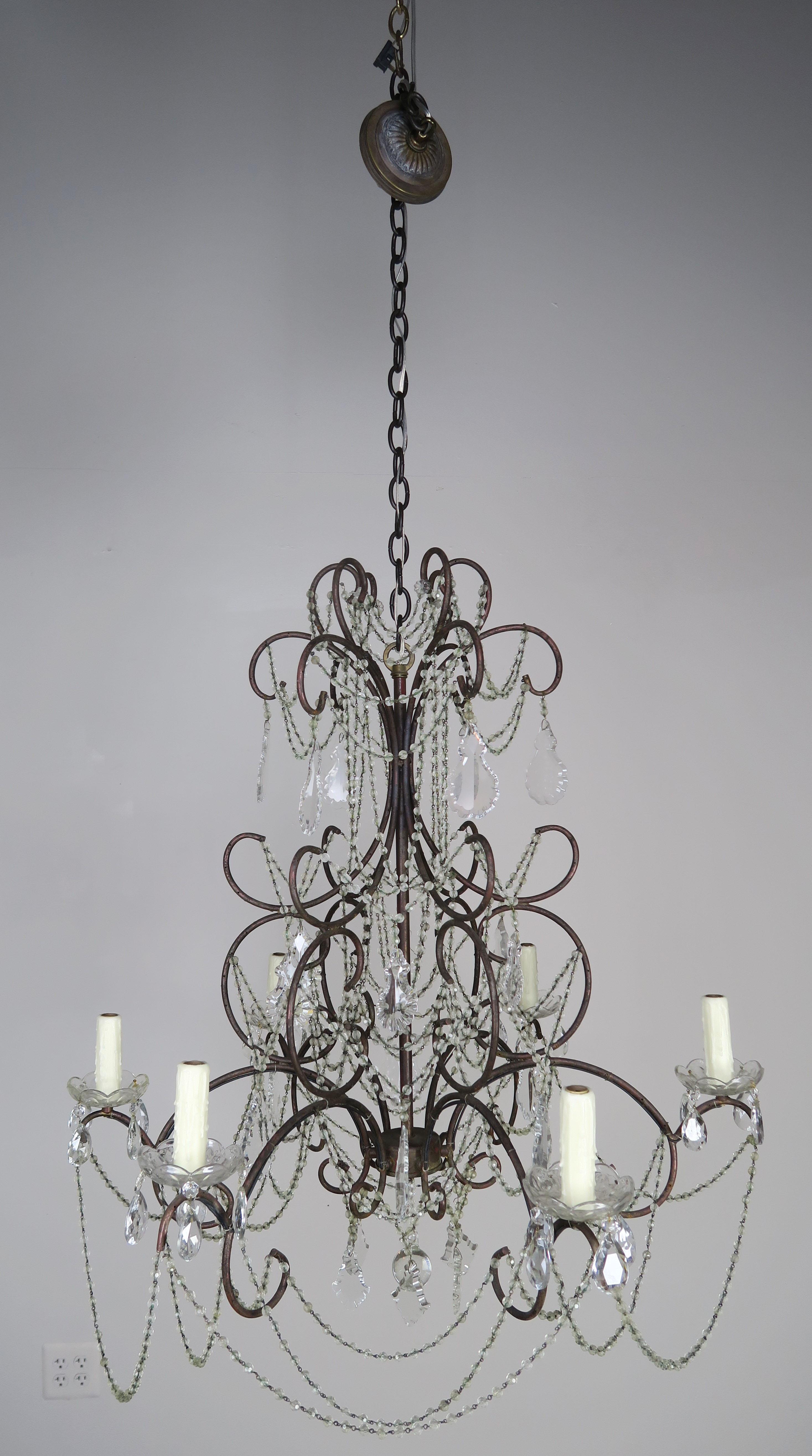 French six light iron chandelier adorned with garlands of crystal beads and crystals throughout. Clear crystal ball at bottom of chandelier. The fixture is newly rewired with drip wax candle covers. The fixture includes both chain and canopy and is