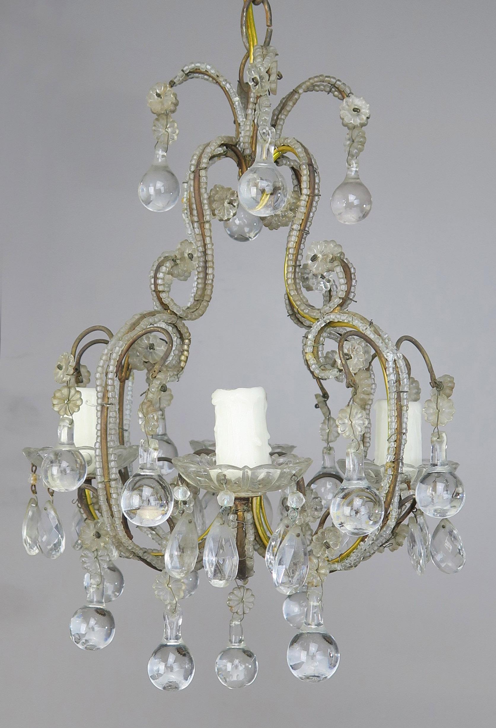 French four-light crystal beaded chandelier with clear drops. The metal frame is all scrolled and beaded throughout. The fixture is newly rewired with drip wax candle covers. Ready to install and includes chain and canopy.