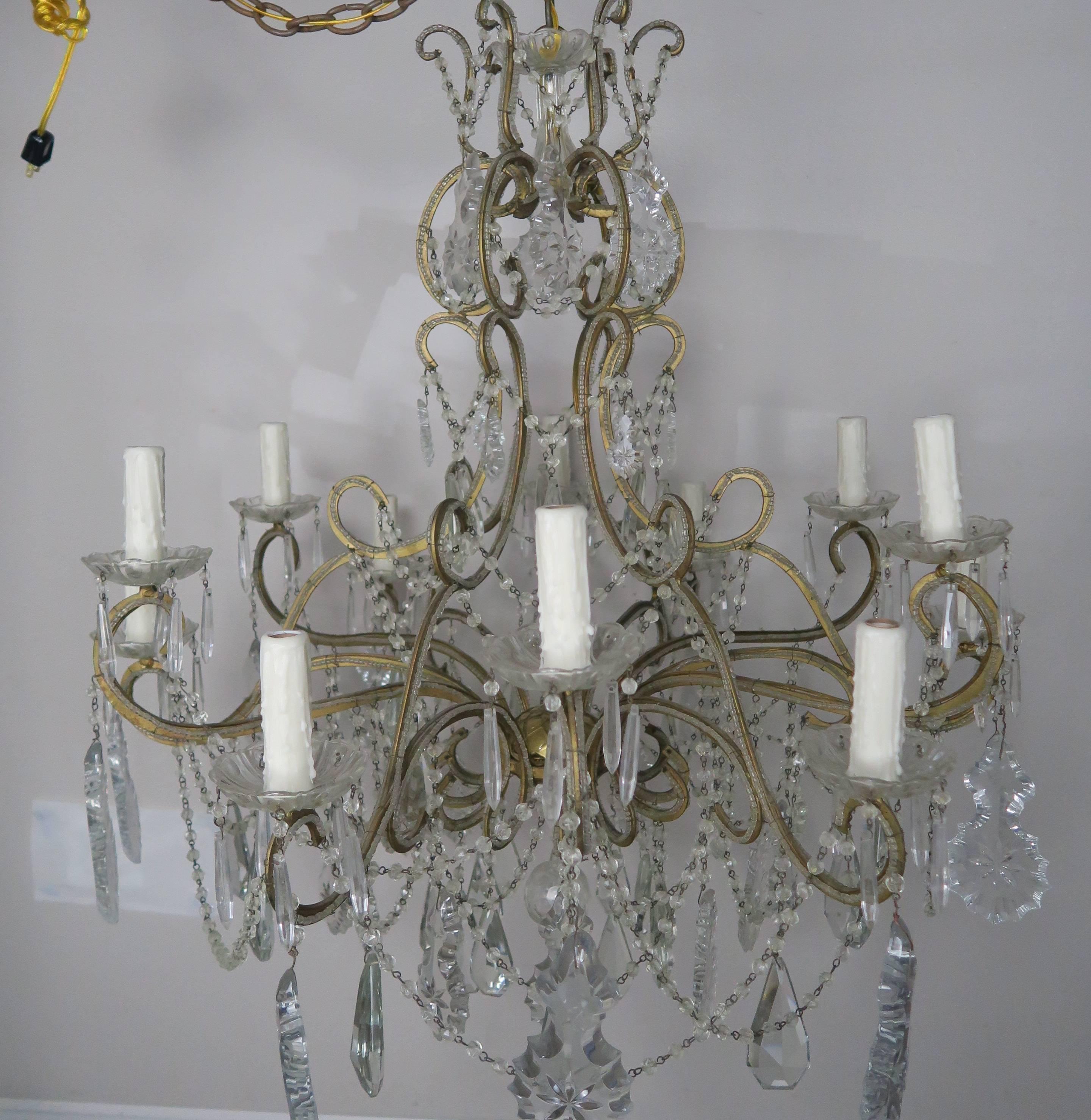 French twelve-light double tier crystal beaded gilt metal chandelier adorned with star cut crystals and strands of crystal garlands throughout. The fixture has been newly rewired with drip wax candle covers. Includes chain and canopy.
