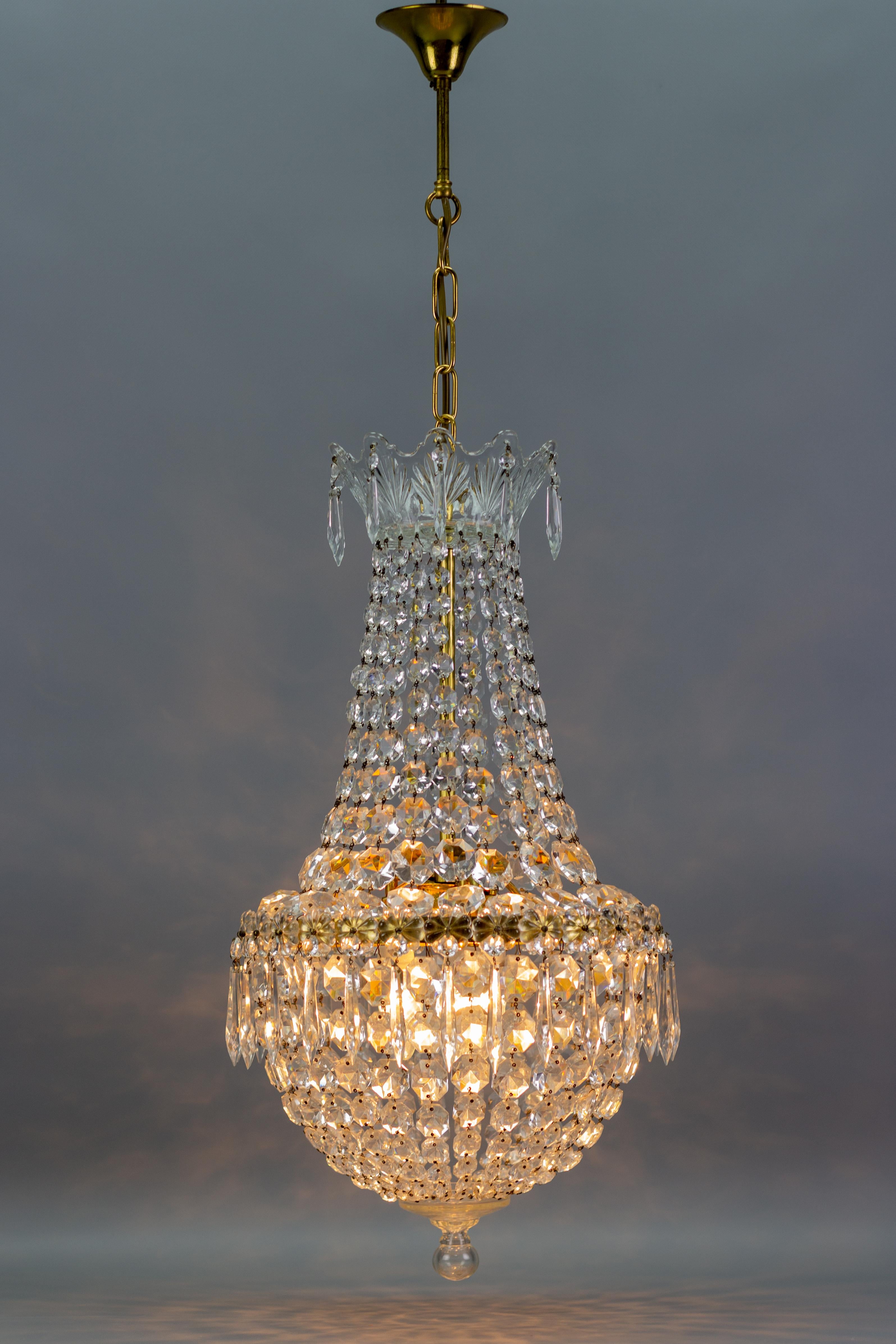 Stunning French three-light crystal glass and brass basket-shaped chandelier from the 1950s. This beautiful piece has a brass frame hung with chains of crystal glass beads forming a basket shape and reflecting the light beautifully. The crown is