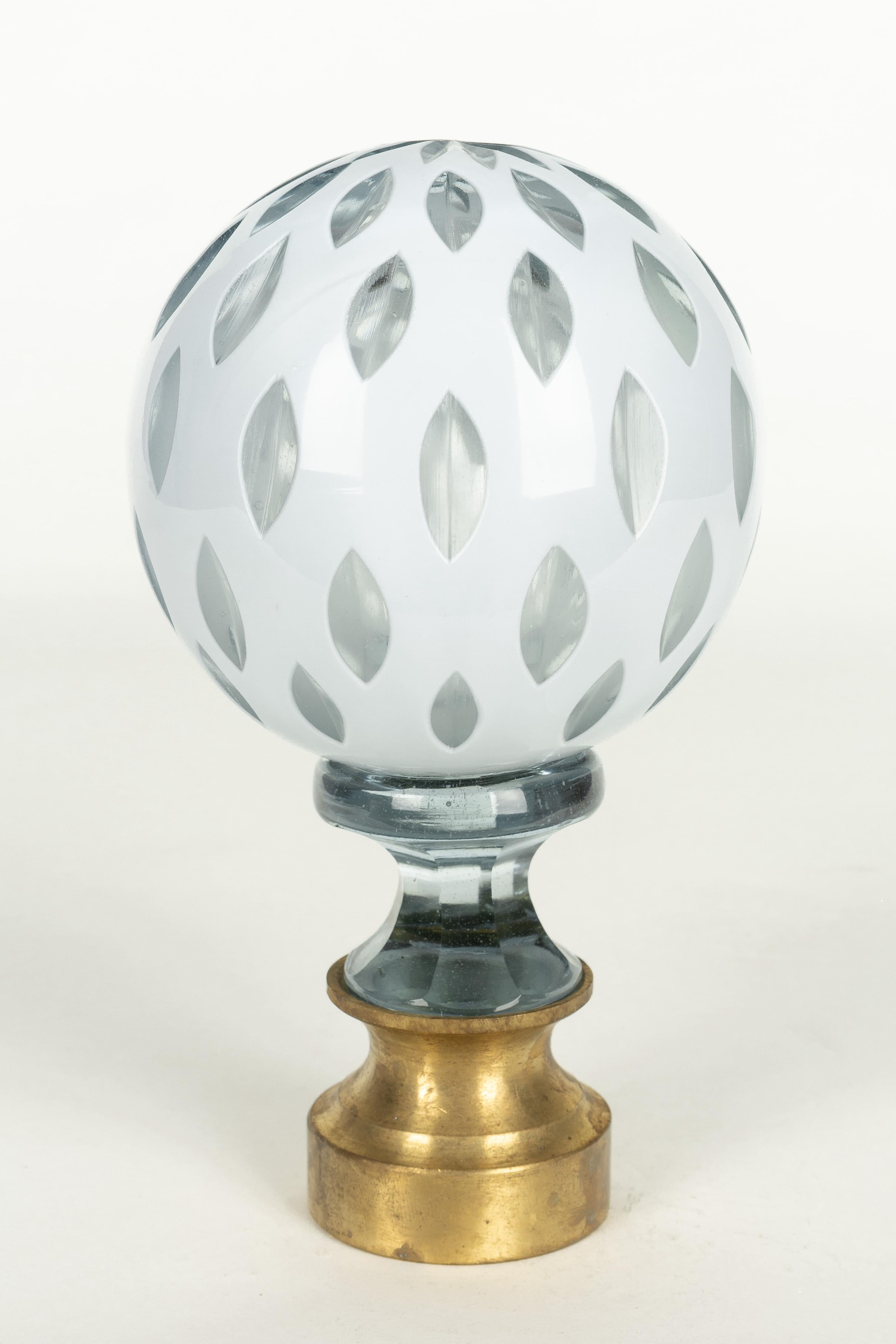 A French crystal newel post finial or boule d'escalier. Made of two layers of cased glass with the white glass surface cut to reveal clear glass underneath. Brass hardware base. These wonderful finials were used as decorative elements at the bottom