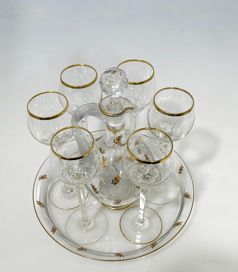 French crystal liquer set, ca 1900

A French crystal liqueur set on a serving tray and 6 glasses. The decanter with a stopper and a spout decorated with gold rose flowers and a beautiful swirl ear. The serving tray has the rose flowers in gold on