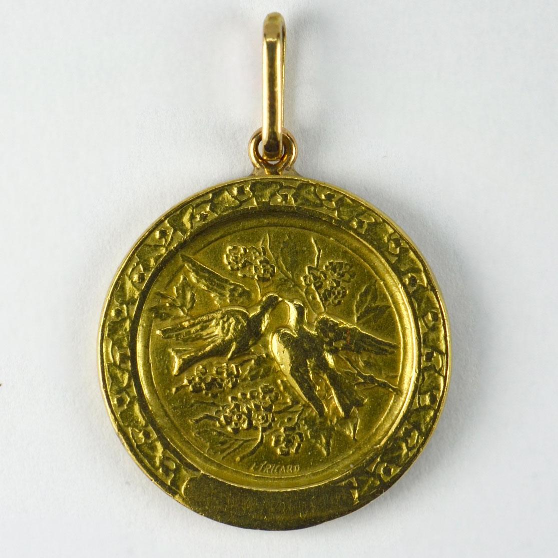 A French 18 karat (18K) yellow gold charm pendant designed as a round medal depicting a thoughtful cupid with bow and arrow to one side, with a pair of lovebirds on a rose branch within a frame of ivy to the reverse. Signed L. Tricard and numbered