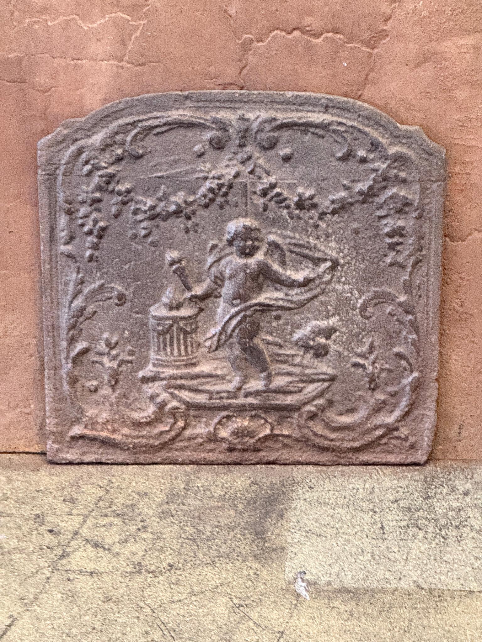 Late 18th or early 19th century French neoclassical fireback with a cupid.

The fireback is made of cast iron and has a natural brown patina. Upon request, it can be made black/pewter colored with stove polish at no extra cost. It is in good