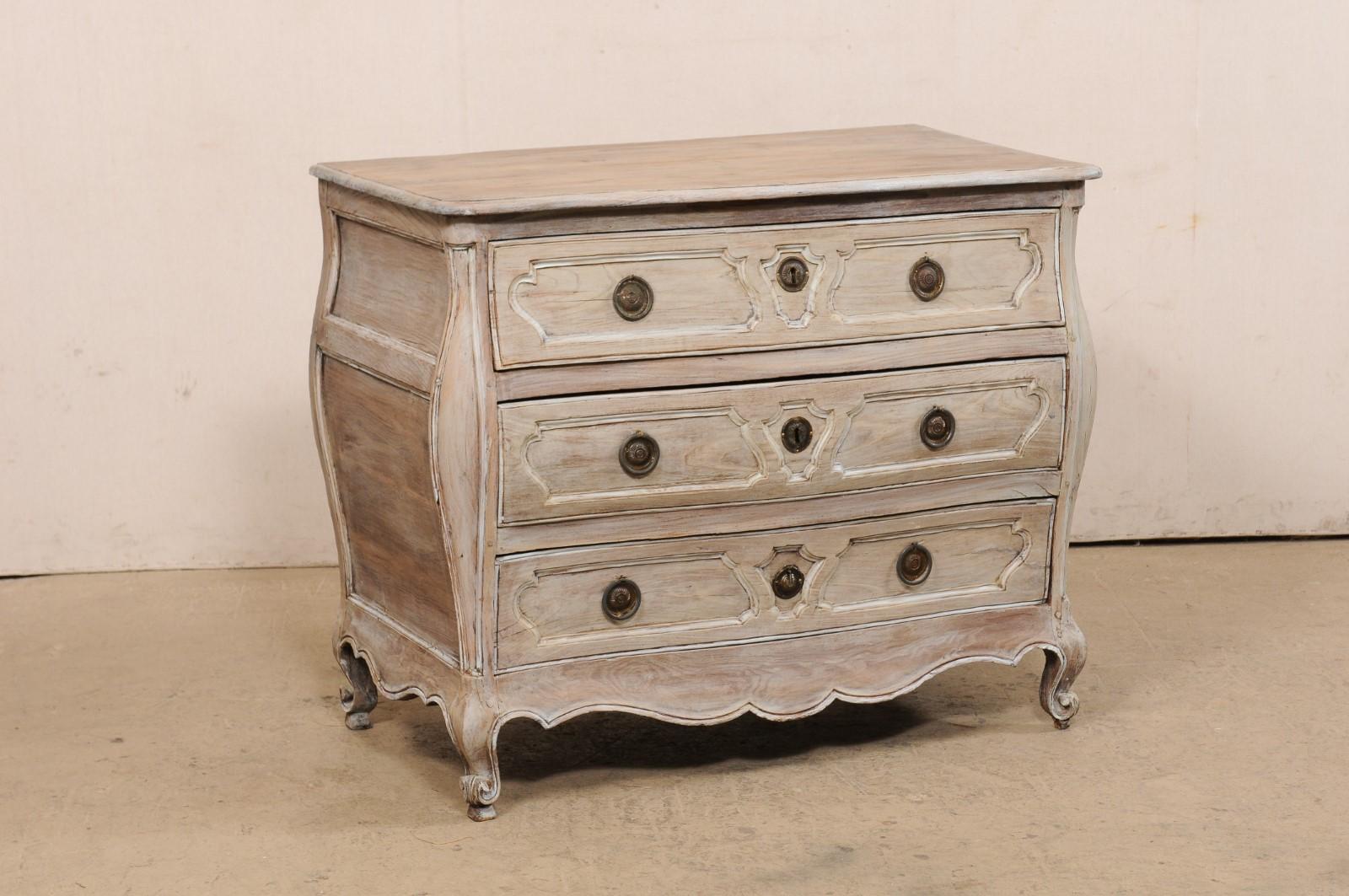 A French three-drawer carved and painted wood bombé chest from the turn of the 18th and 19th century. This antique commode from France has a shapely bombé designed body, with a fluidly, curvaceous form. The case houses three full-sized drawers, each