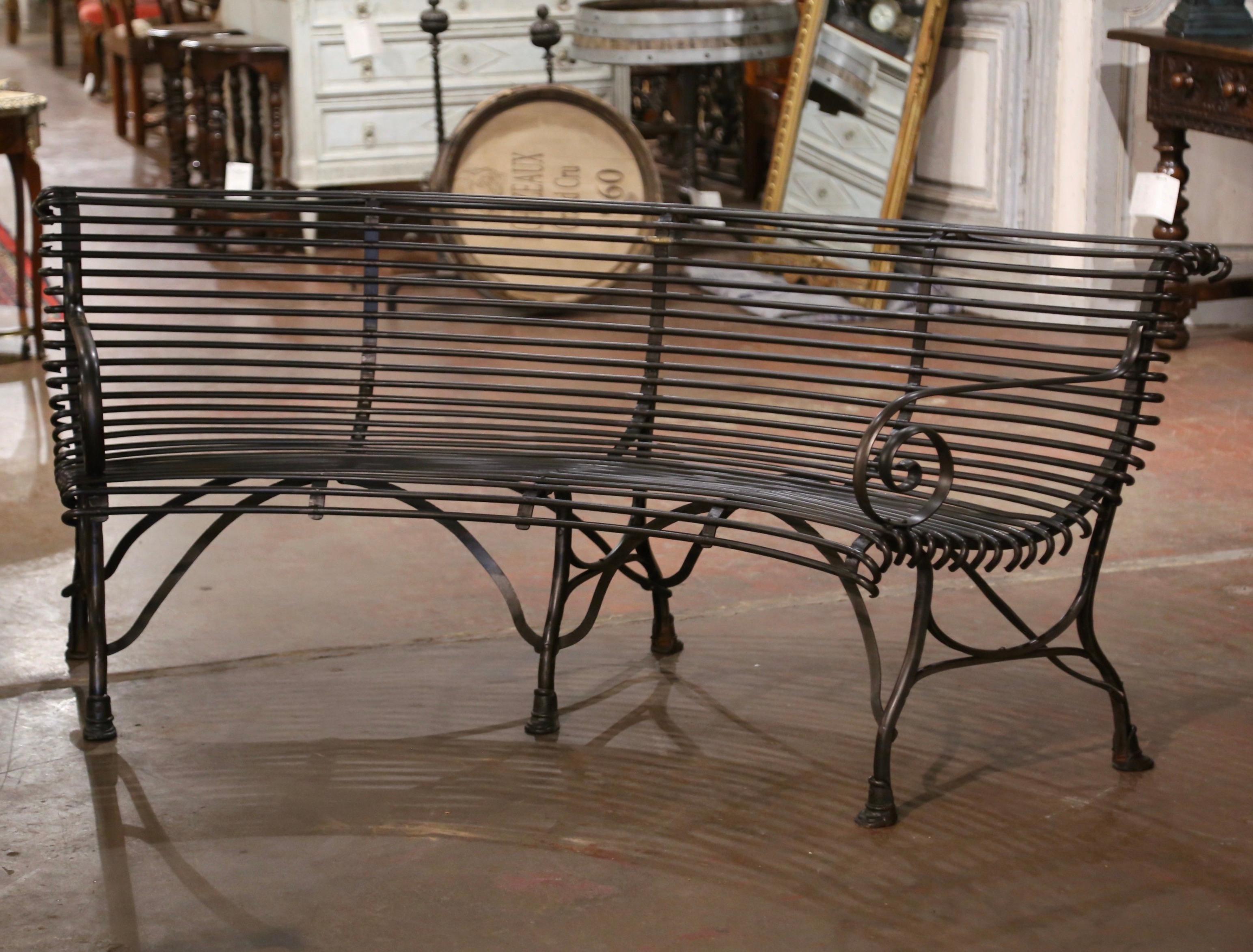 This elegant forged iron bench was crafted in France. The rounded bench stands on six legs ending with hoof feet and connected with stretchers at the base. The seating has gracious lines, scrolled armrests, and a curved back; the comfortable