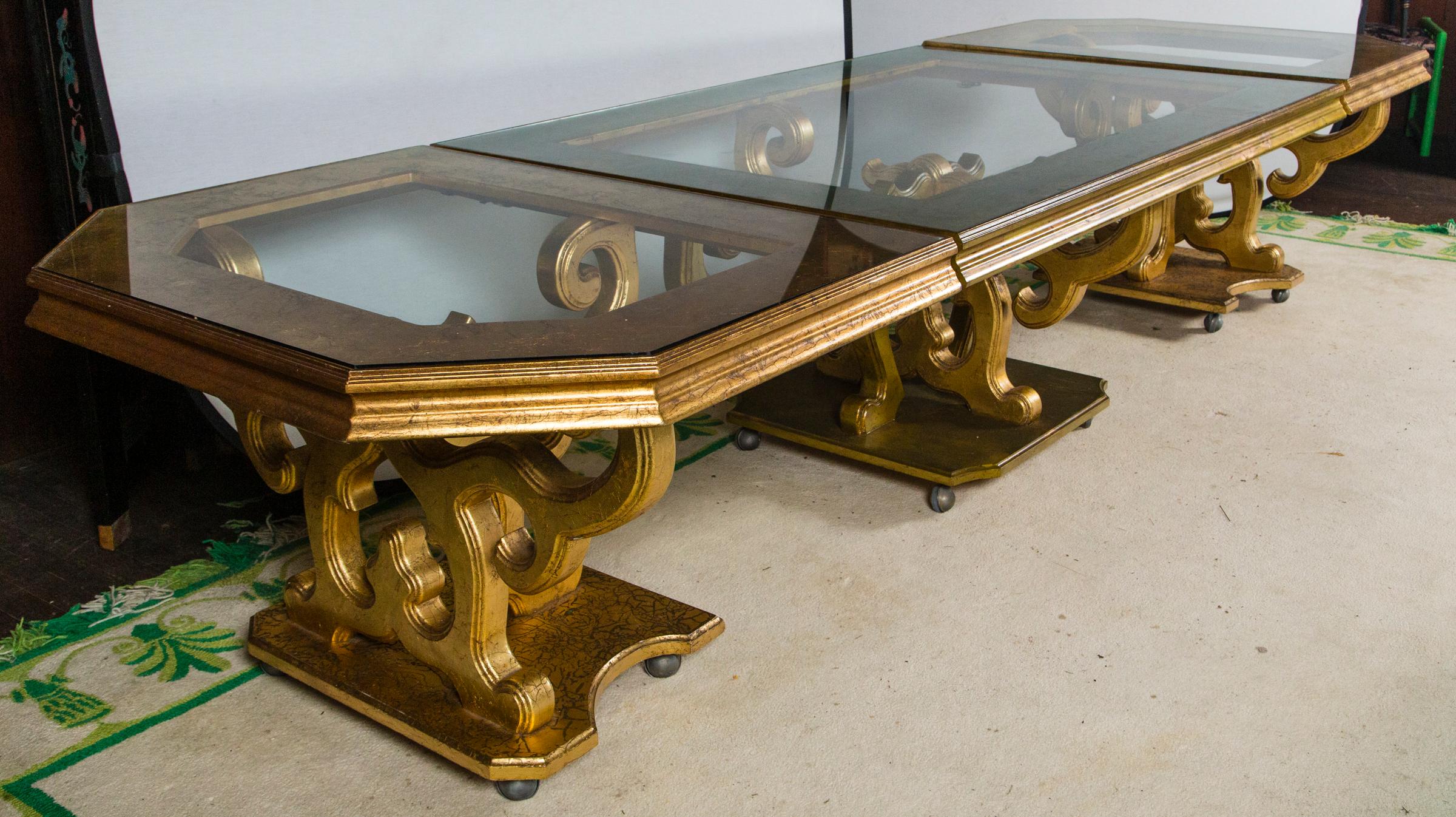 French three-piece gilt carved wood dining table with glass top. Two end pieces are 35 inches long. Middle piece is 70 inches long. Each piece is on casters. Center section gilding under glass has aged in a slightly different 
hue than two end.