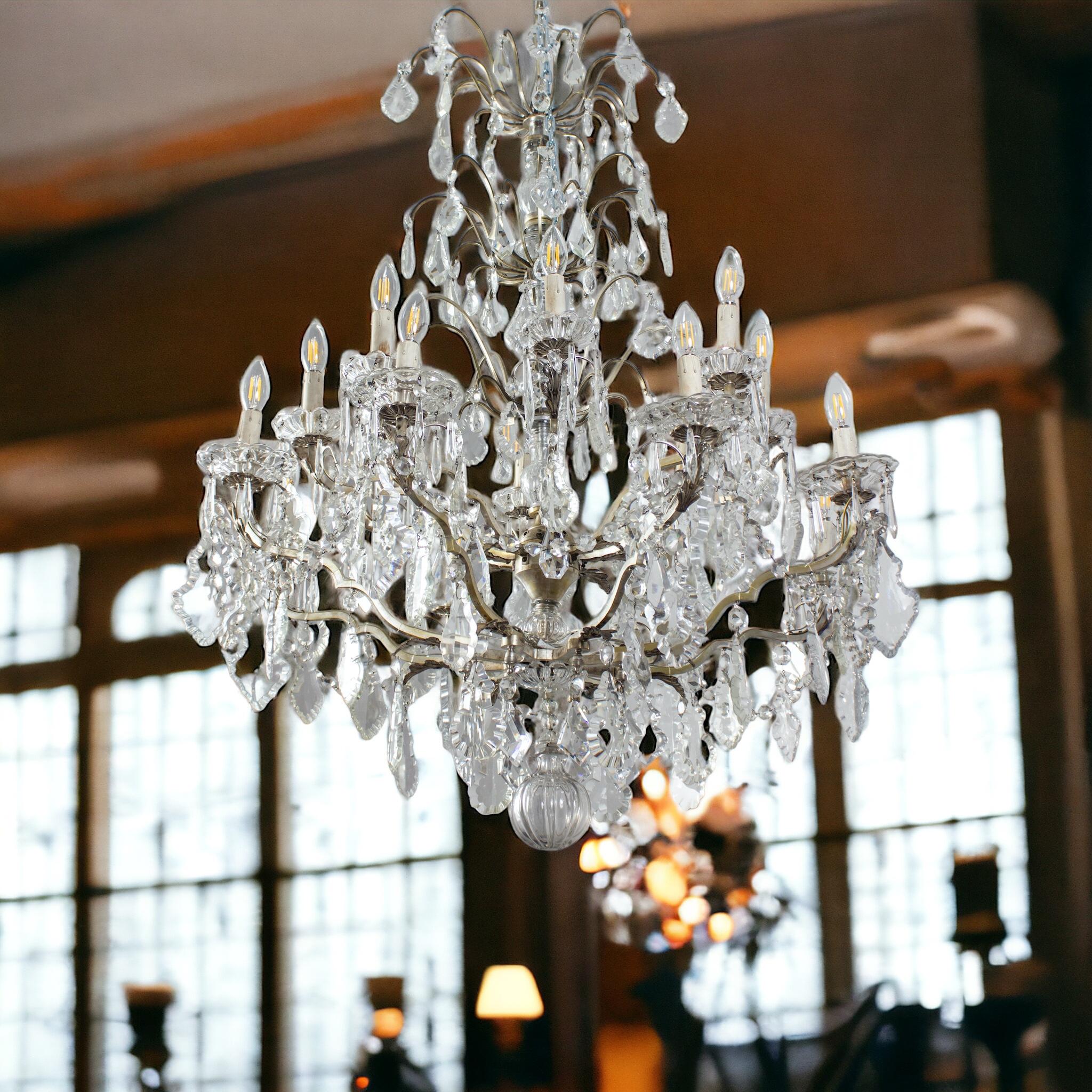 A French Louis XV style silvered-metal and cut- crystal  sixteen-light chandelier. The caged body surmounted with 16 scrolled candle-arms with a leave finish ,all surmounted with cut-glass pendants,. Paris, circa 1900.
 Takes 16 base bulbs (E-14) up