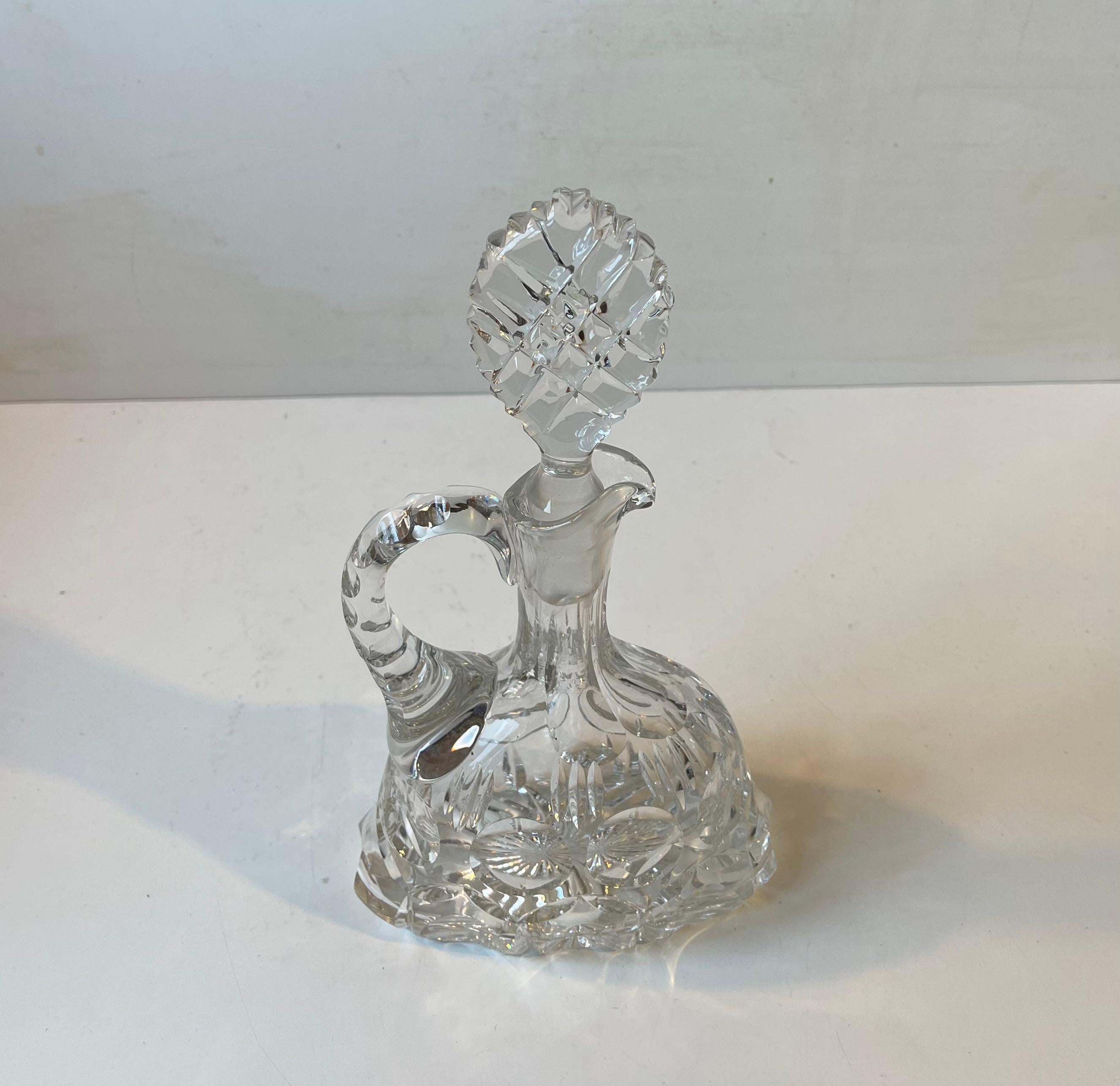 This wine or Port decanter dates to the 1950s or 60s. Its many cut edges are beveled softly. It can contain around 0.7 liter. Very reminiscent in style to similar designs from Saint-Louis - Tommy Glassware. It was possibly made by Cristal de