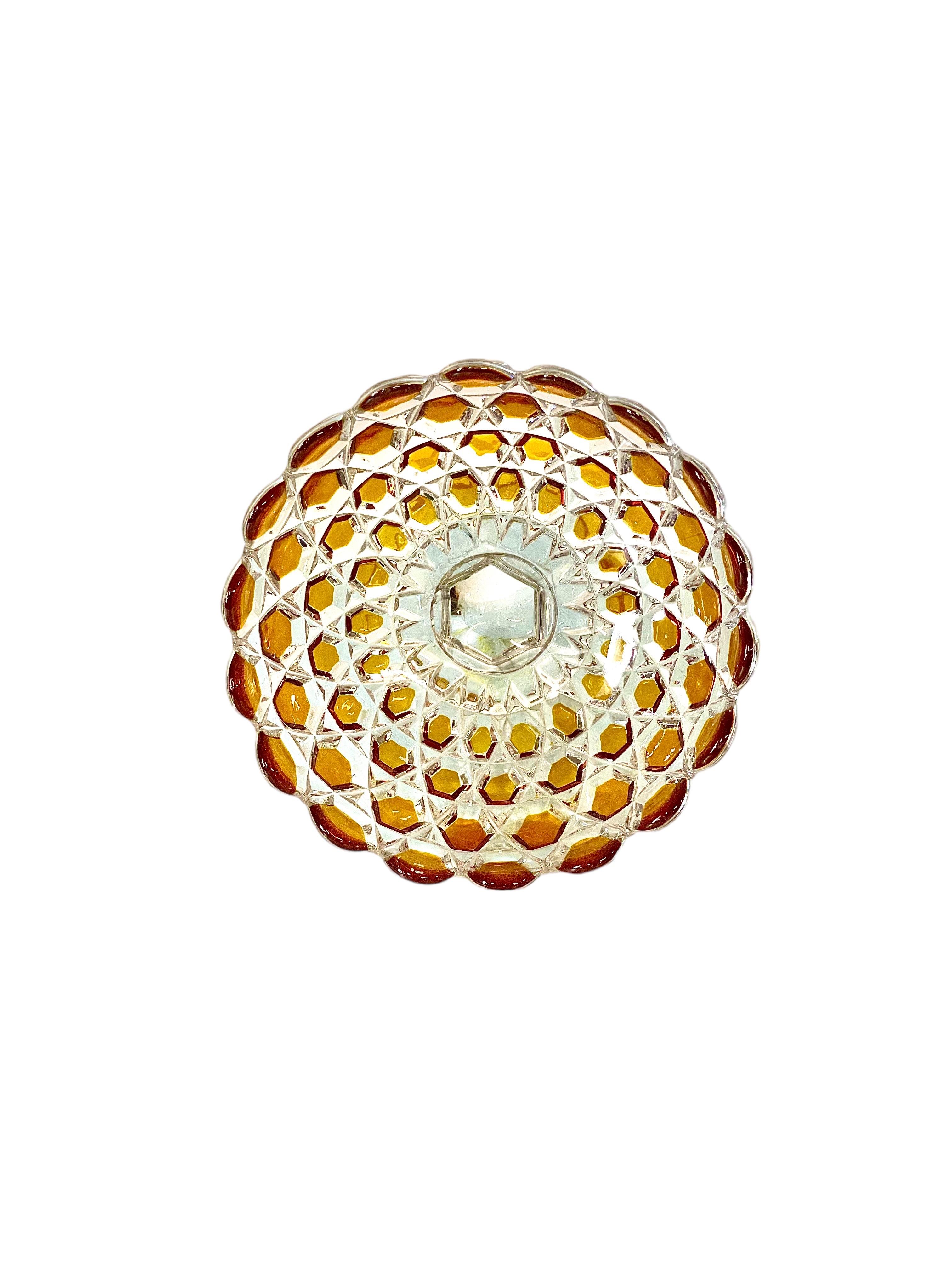 Bonbonnière en cristal taillé d'époque, ornée de motifs diamantés bicolores transparents et ambrés et d'un bord festonné très décoratif. Le plat, qui date du début du XXe siècle, repose sur une base merveilleusement façonnée, en forme de fleur à