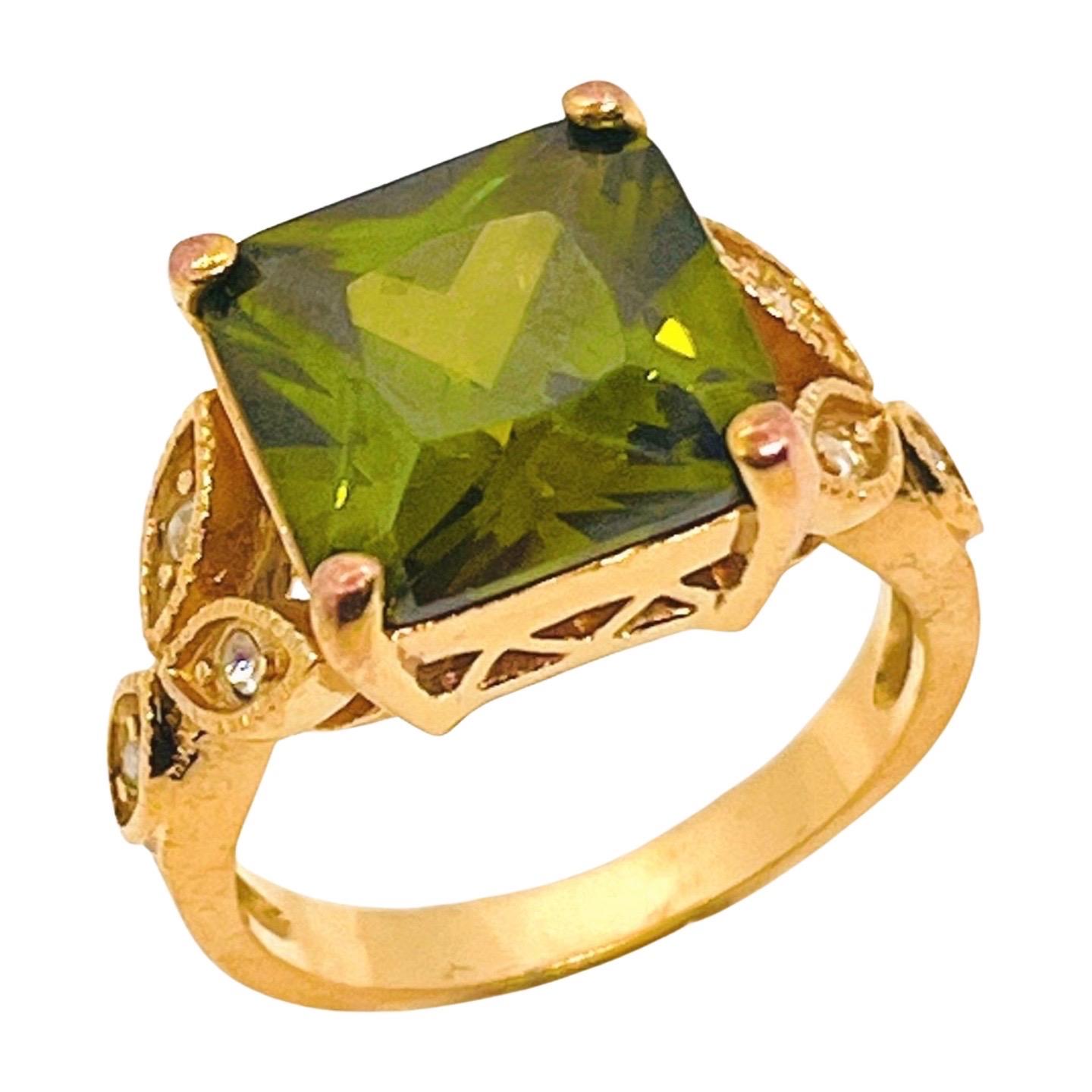 Anello d'oro con peridoto finto, taglio francese (principessa), zirconi, gambo a cattedrale, revival in stile Belle Epoque. Motivo a tre foglie sulle spalle dell'anello con piccoli strass dal taglio rotondo e metallo strutturato.

Questo è uno