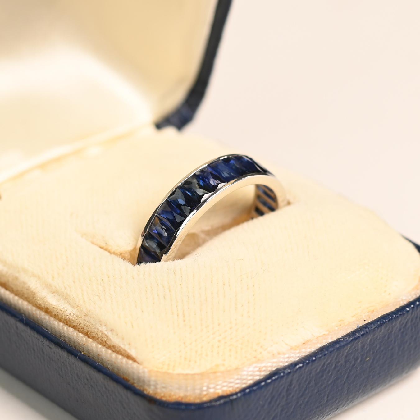 Cet exquis anneau d'éternité en platine met en valeur un superbe saphir allongé de 4,20 carats, taillé à la française, méticuleusement serti en canal dans une orientation nord-sud raffinée. La taille française allongée unique rehausse l'éclat de