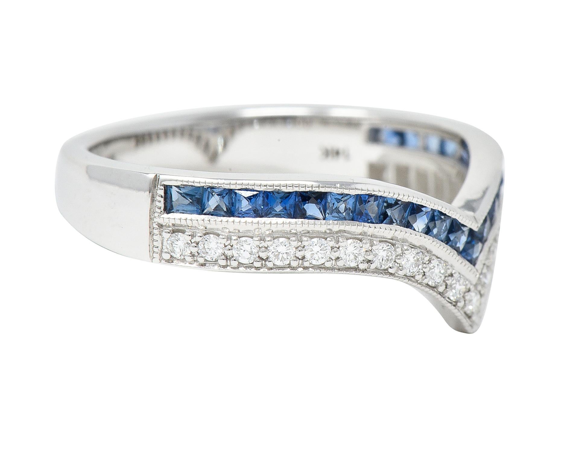 Designed as a pointed chevron motif contour style band featuring one row each of sapphires and diamonds. Sapphires are French cut and weigh approximately 0.53 carats total. Transparent medium blue in color and channel set to front. Diamonds are