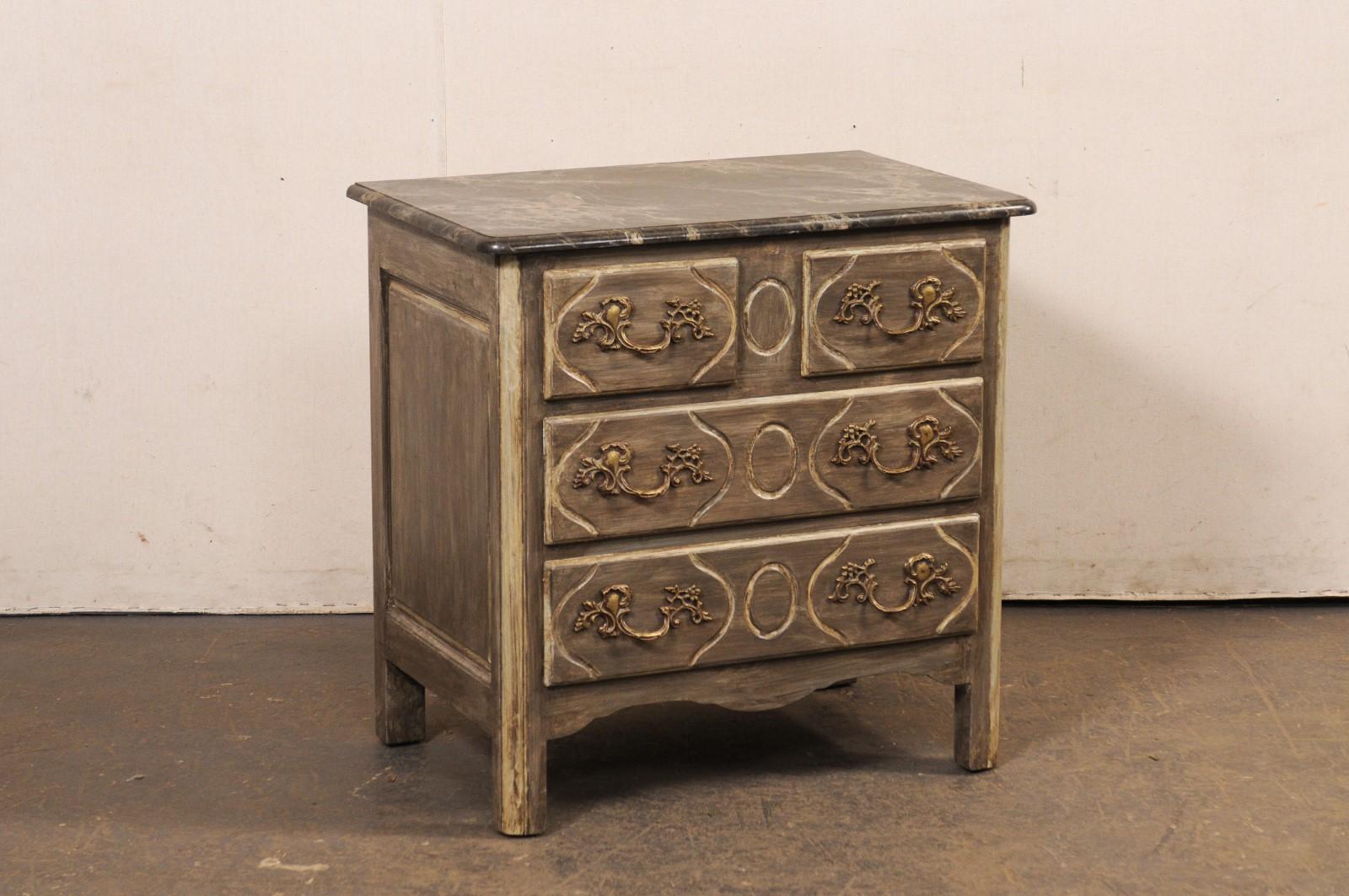 Commode francese in legno intagliato e dipinto con piano in finto marmo. Questa cassapanca vintage proveniente dalla Francia ha un piano di forma rettangolare con angoli dolcemente arrotondati, caratterizzato da una sorprendente finitura in finto