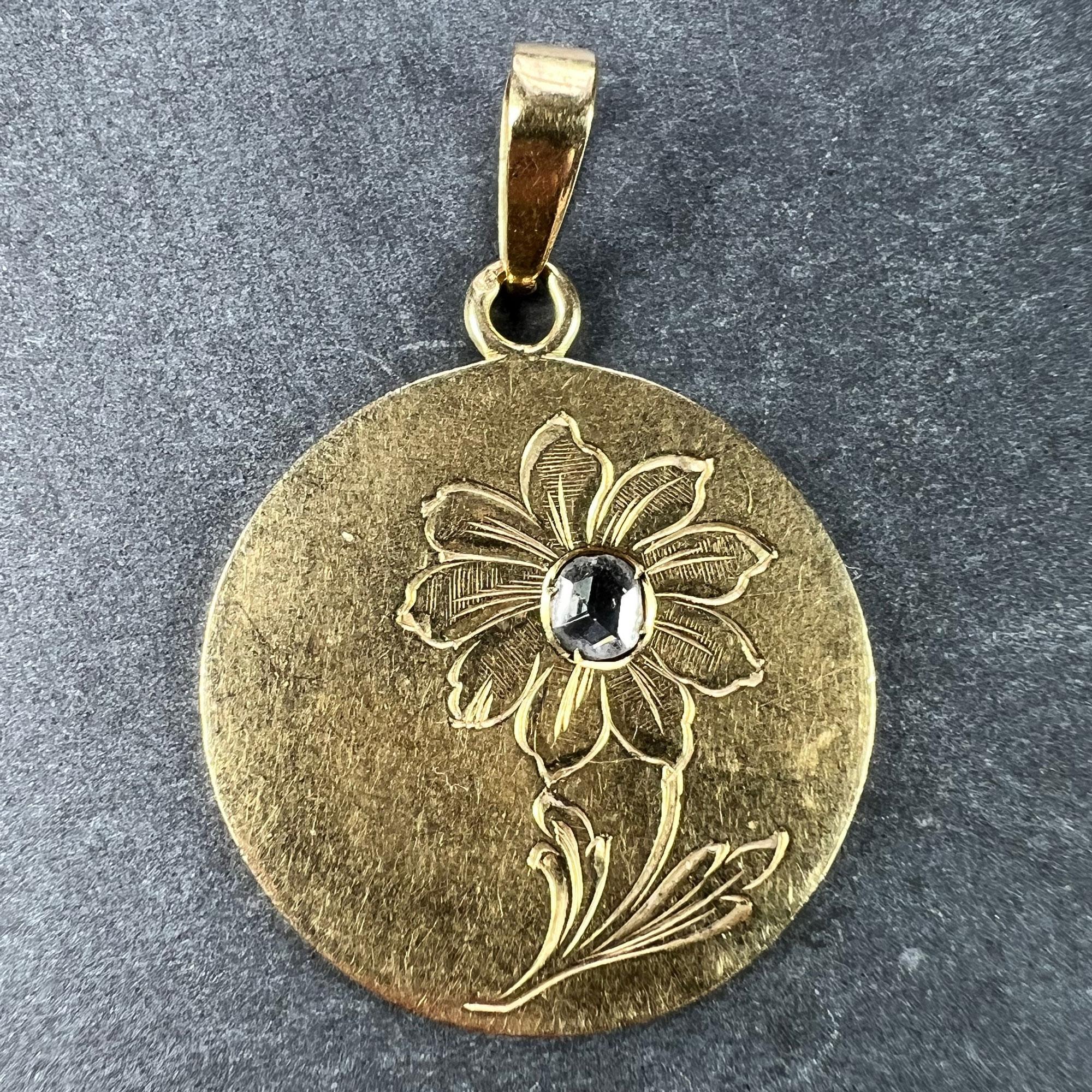 A French 18 karat (18K) yellow gold charm pendant designed as a disc with an engraved daisy or margherite flower set to the centre with a rose-cut diamond weighing approximately 0.10 carats. Stamped with the French import mark for 18 karat gold to