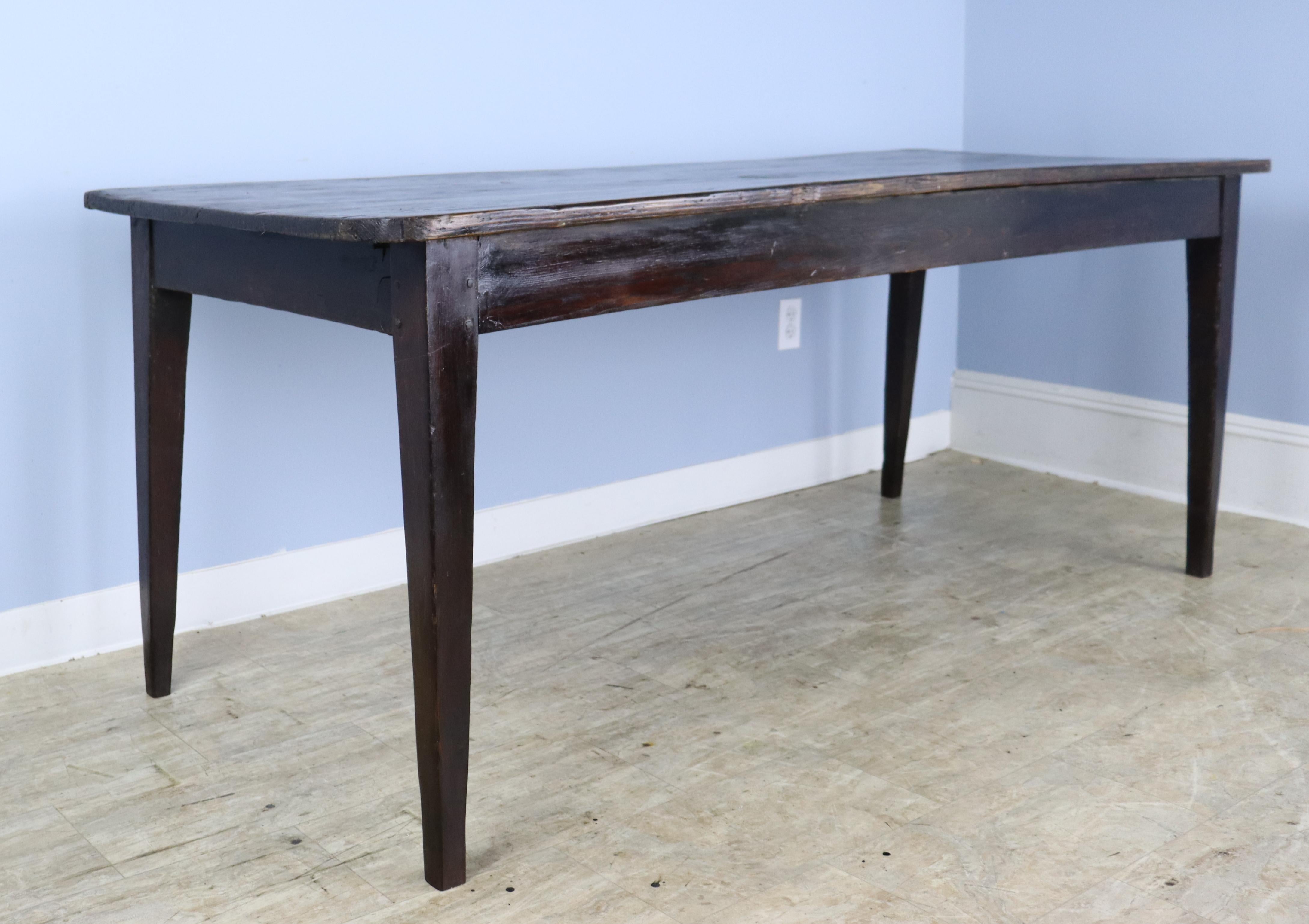 A simple pine farm table, stained dark with good color, grain and patina. Rounded corners and nicely pegged at the apron, which is 25 inches high and good for knees. There are 67.5 inches between the legs on the long side. There are some small areas