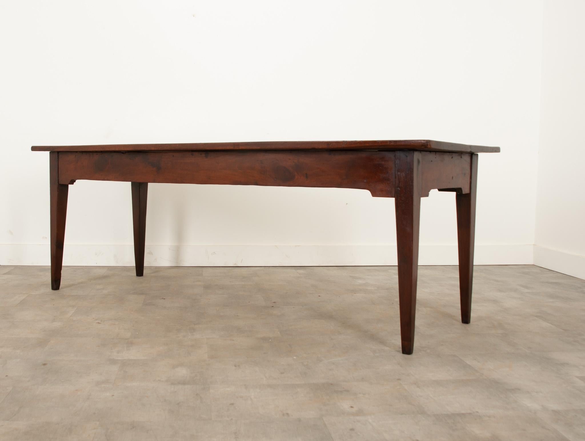 Table de ferme française fabriquée au 19e siècle en noyer massif richement patiné. La partie supérieure présente de manière élégante plusieurs générations de vie. Le tablier est sans couture et sans tiroir. Des pieds merveilleusement effilés