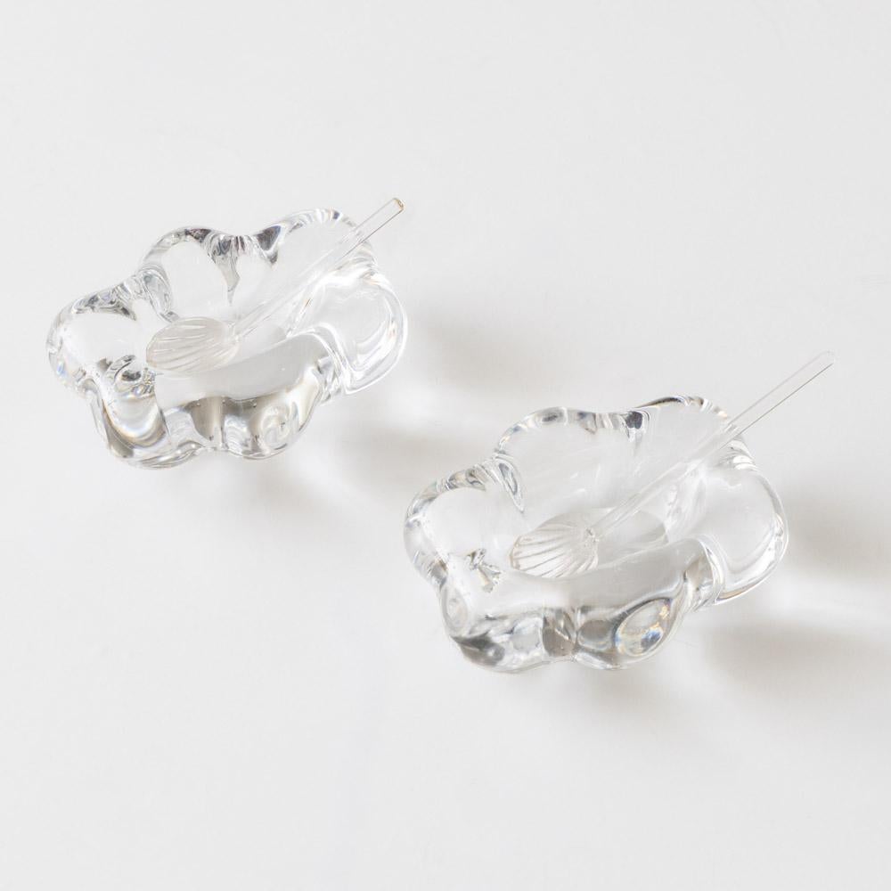 Magnifique paire de salières en cristal de Daum, France, années 1950. Plats en cristal à fleurs délicatement sculptés et cuillères en cristal à coquilles. Ensemble complet et rare de la ligne Fleur de Daum. Parfait pour les sels de finition ou le