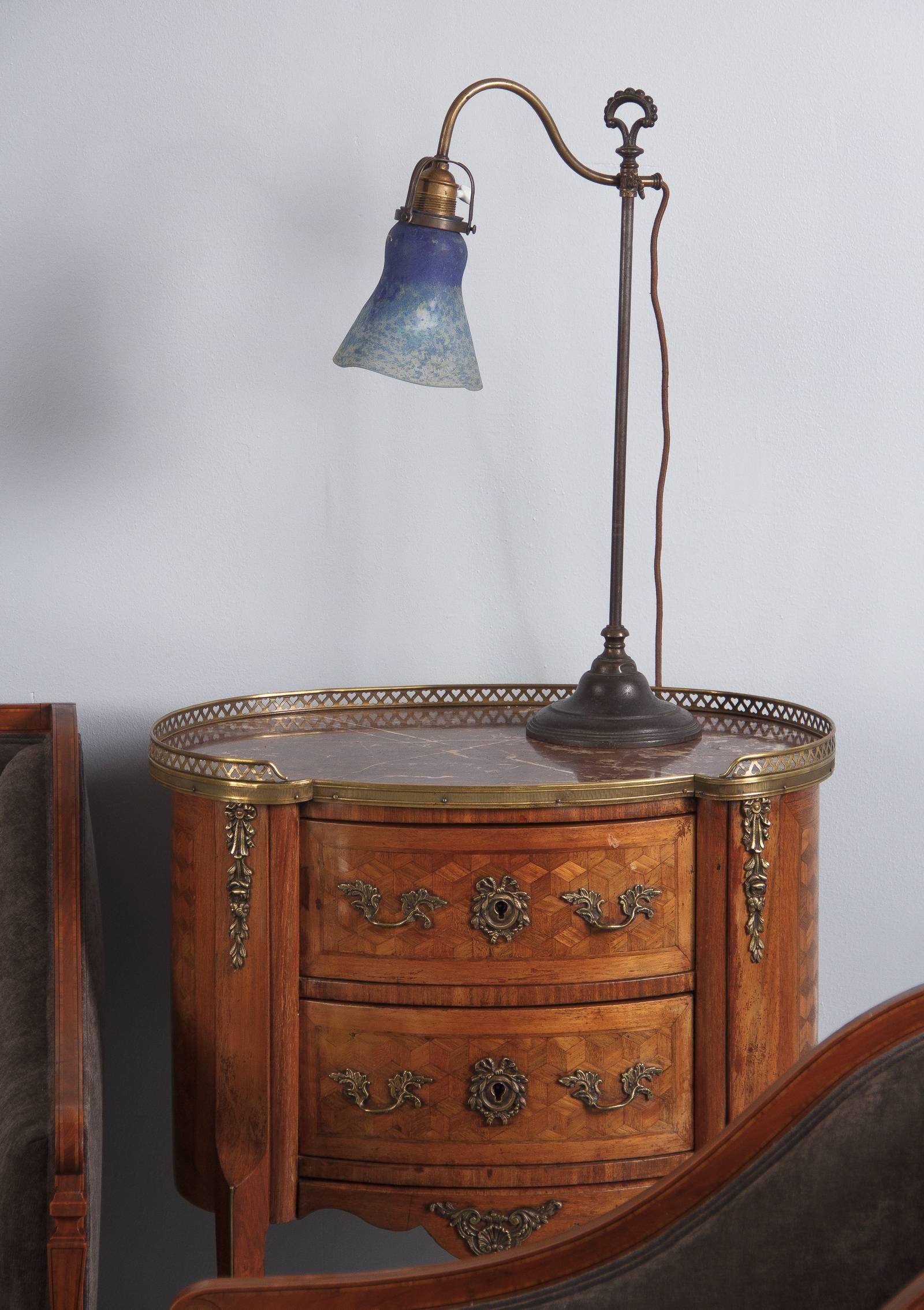 An elegant Art Nouveau desk lamp with signed art glass shade by Daum, circa 1900. The iron stand has a molded base and an arched and beaded finial. A curved brass arm can be adjusted to chosen height with a stylized Fleur de Lis handle. The fixture