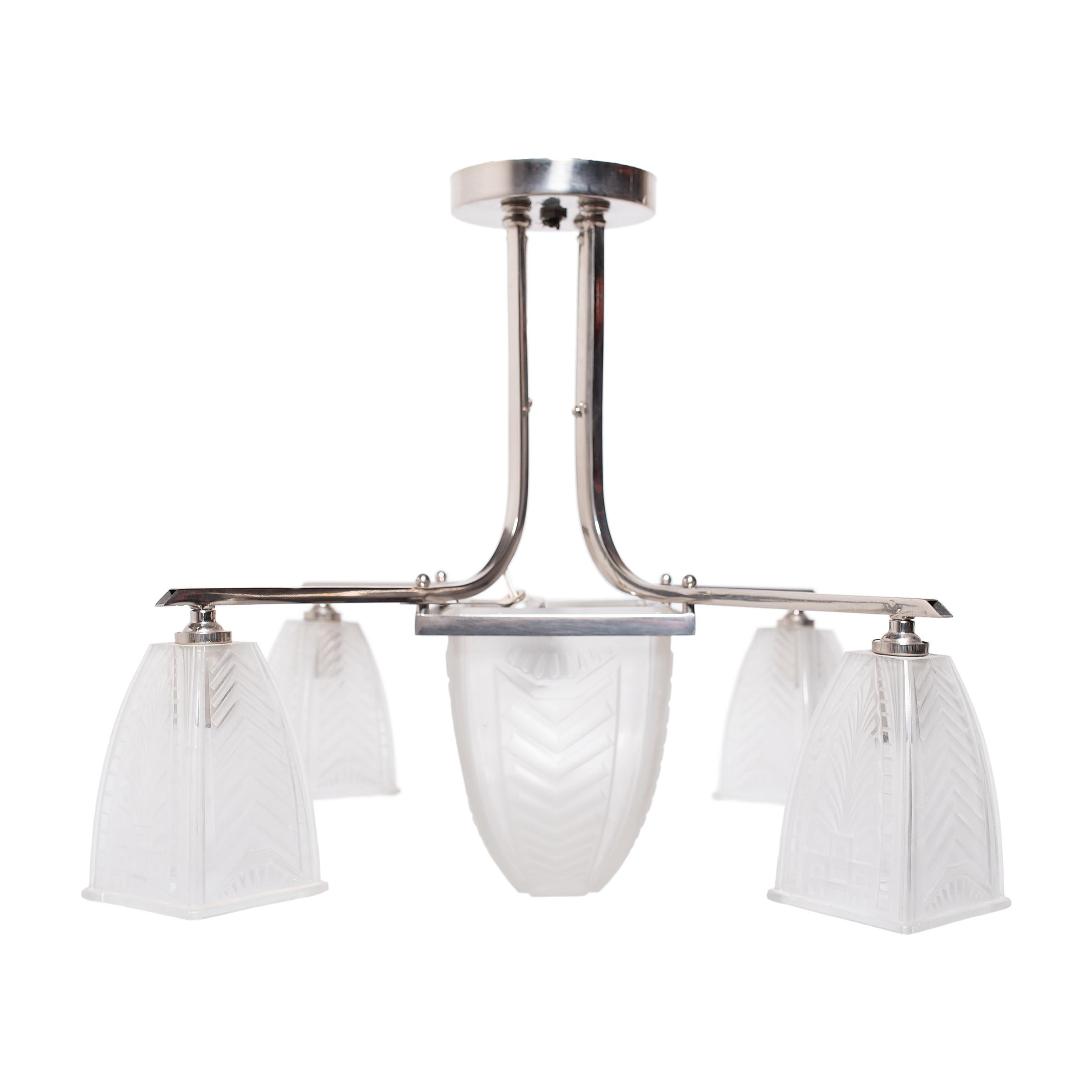 This elegant five-light chandelier exemplifies French Art Deco lighting with a sculptural form, metallic sheen, and a soft, delicate appearance. The large pendant features a nickel-plated metal frame and clear frosted molded-glass shades with