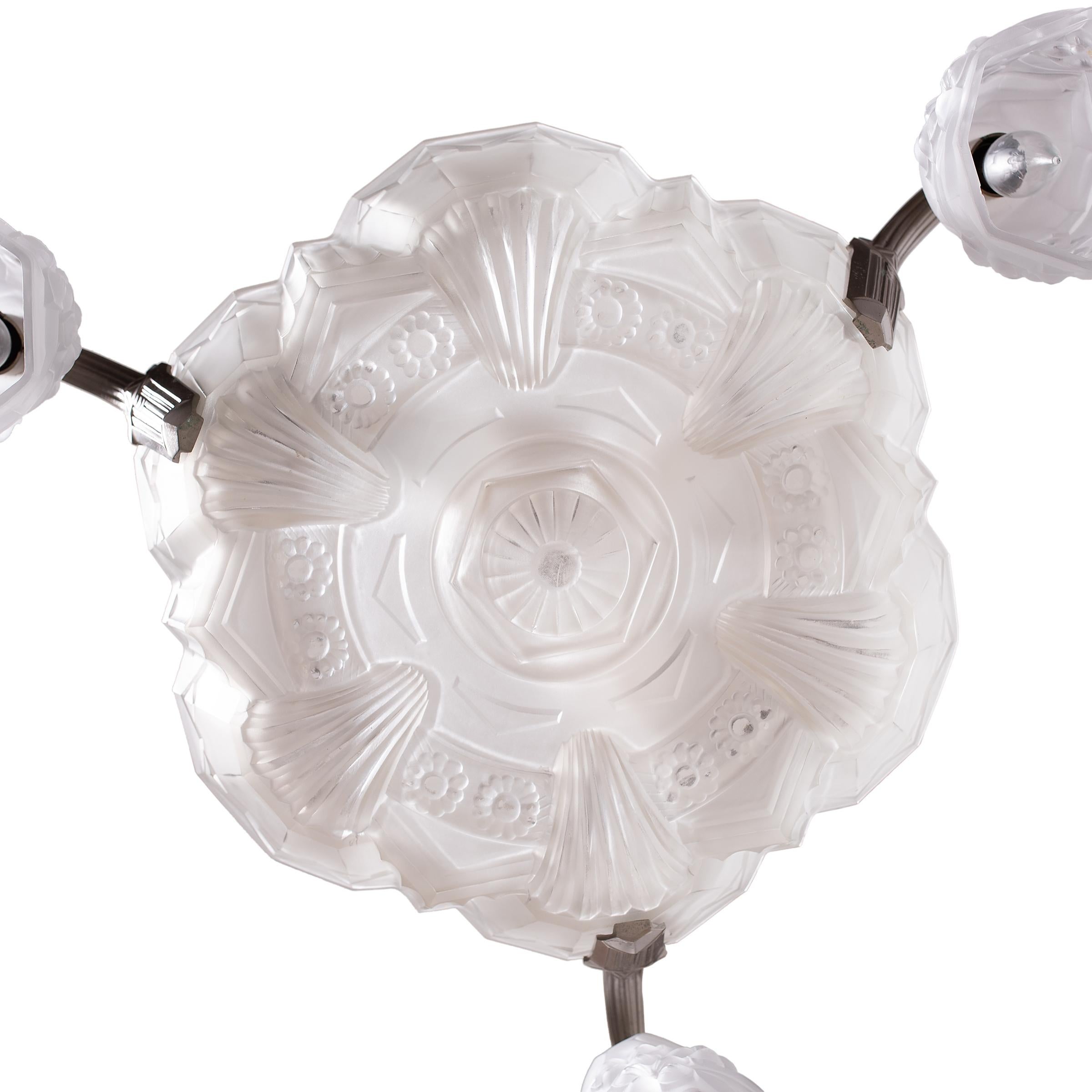 This magnificent hanging light fixture is a rare French Art Deco chandelier of frosted glass set within a nickel-plated bronze frame. The grand chandelier features clear frosted molded-glass shades with intricate designs of distinctly Art Deco