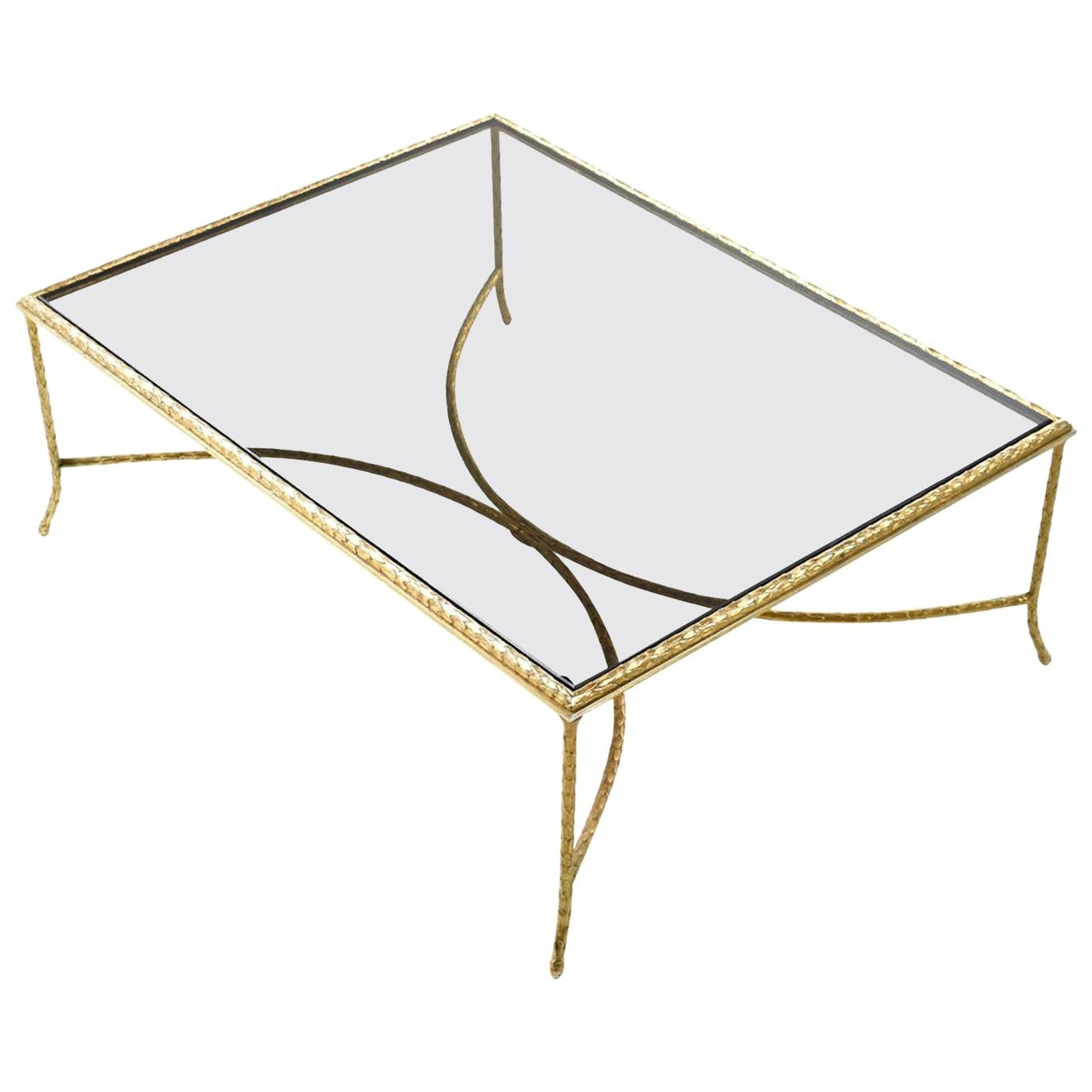 Monumental brass coffee table with delicately ornamented laurel leaf pattern throughout. The table is atypically obtuse at four feet long and three feet wide. Although massive in scale, the narrow gold rods make the table appear dainty. Air moves