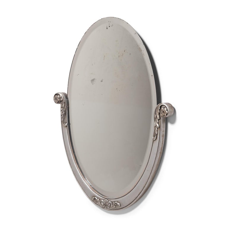 This elegant vintage wall mirror exemplifies the clean lines and imaginative forms that defined the Art Deco design movement of the early 20th century. The elongated oval mirror features a subtle beveled edge and sits within a painted wooden half