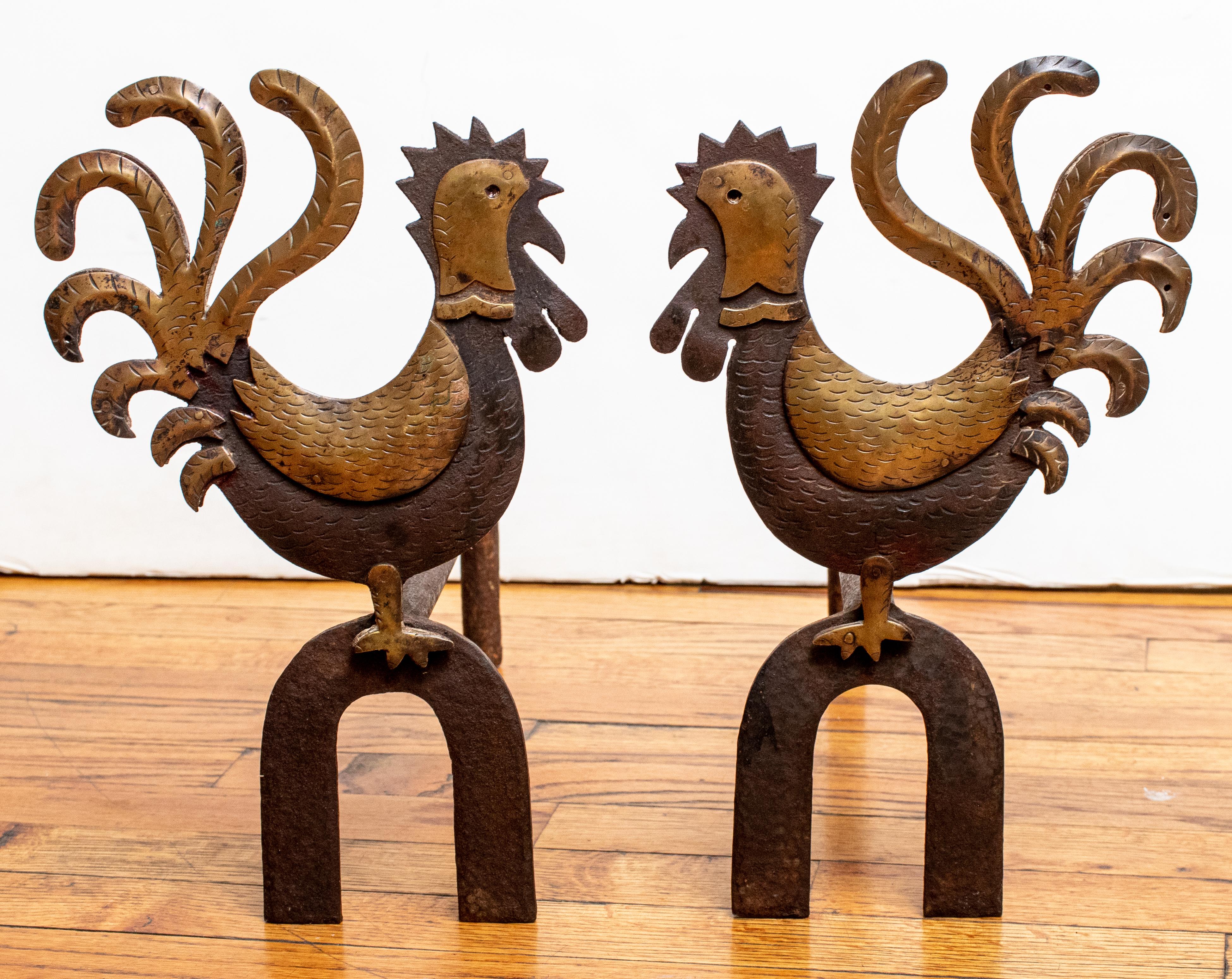 A pair of hand wrought iron and bronze rooster motif andirons. Made in the Art Deco style.