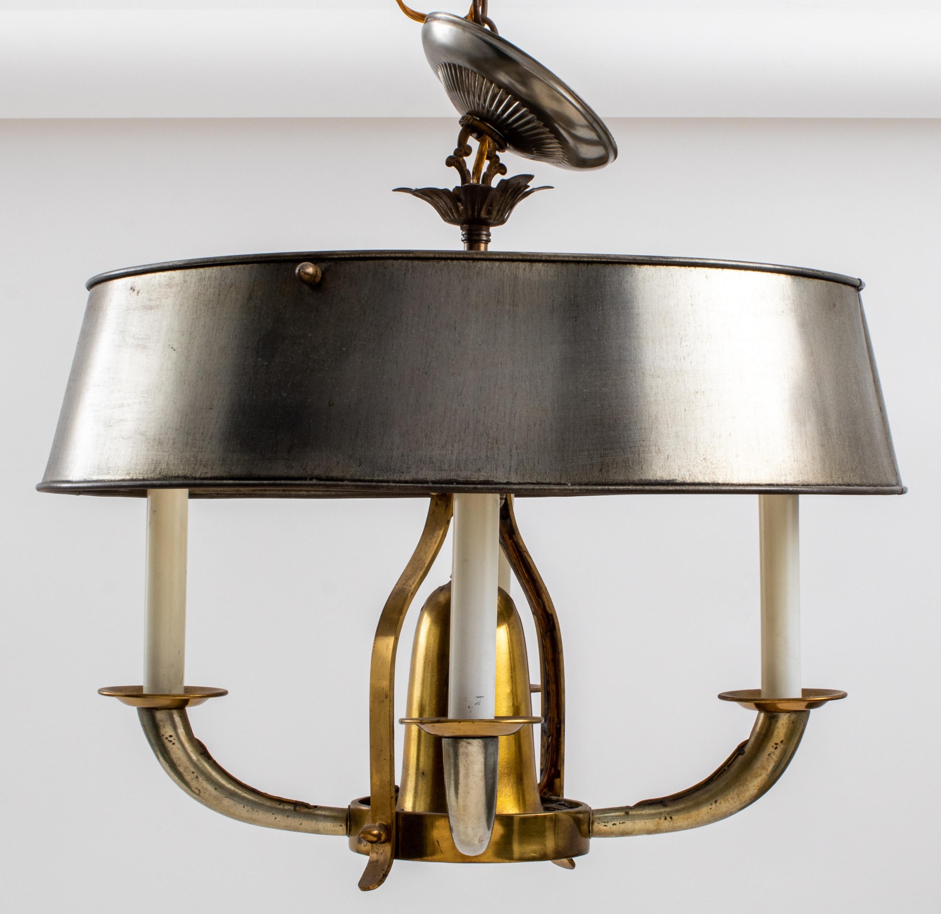 A French Art Deco four light steel and brass bouillotte chandelier in the Jacques Adnet taste, with four brass torpedo arms and bobeches surrounding a bell-form center, the whole beneath a steel bouillotte shade.

Dimensions: 15