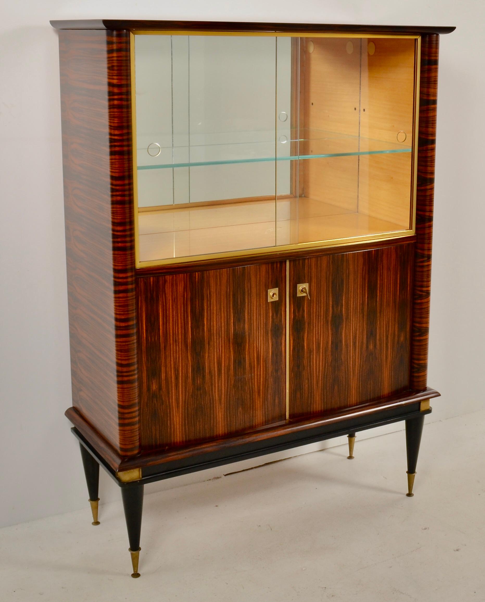 Diseñado en estilo Art Déco, este mueble, fabricado en Francia en la década de 1960, presenta una artesanía superior. Se utiliza ébano de Macassar muy pulido para el mueble exterior, con madera de satén brillante en el interior del mueble superior.