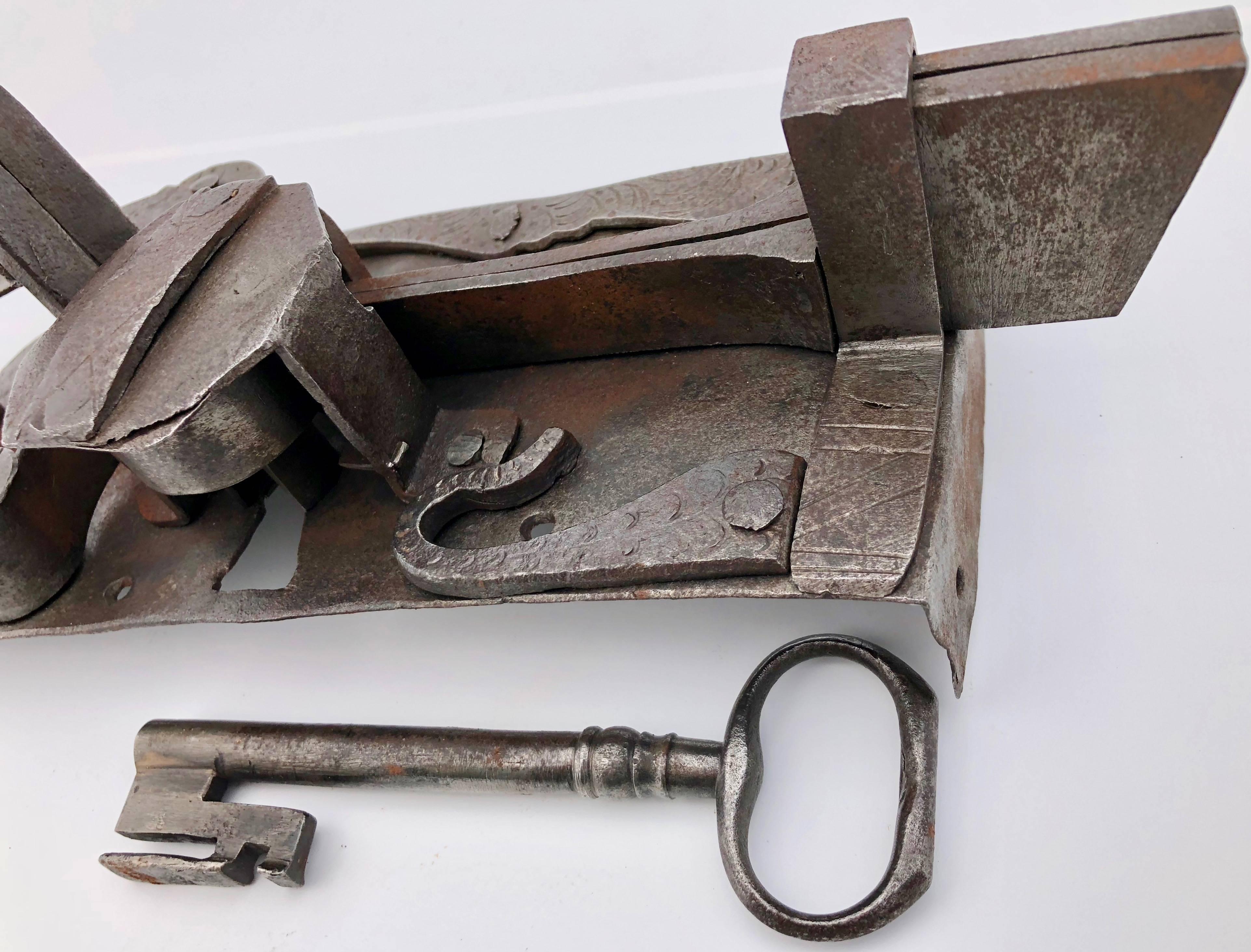 This Louis XVI French hand-wrought locking latch with incised decorations and it's own forged key is a beautiful piece. The latch operates by a lever on the front and by the key from the back. This decorated lock was likely used for a special trunk