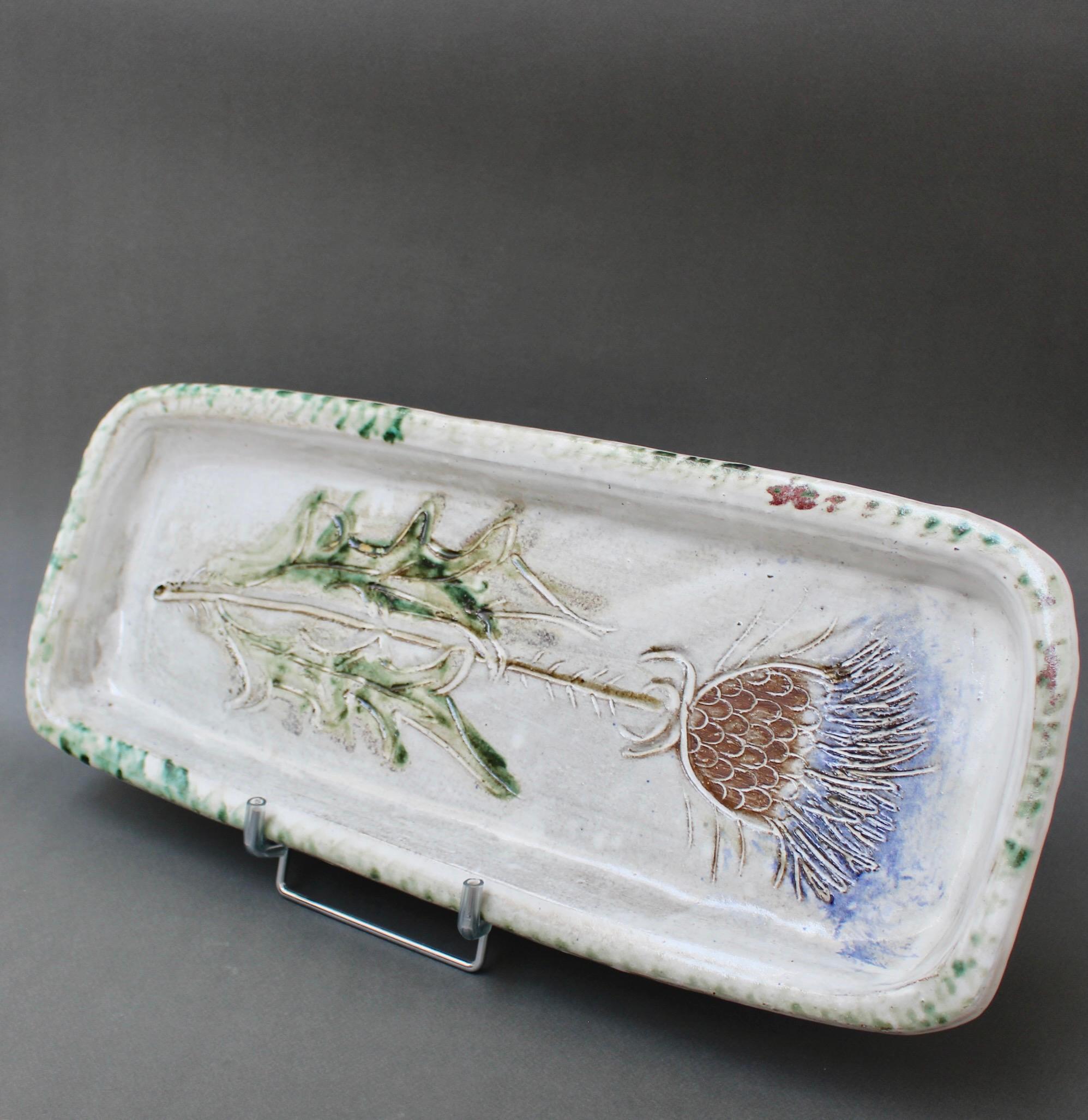 Mid-century decorative tray (circa 1960s) by Albert Thiry. A chalk-white glaze provides the background for a colourful thistle motif in the centre. The rim has touches of earthy green and brown. The flower is incised providing depth tactility. The