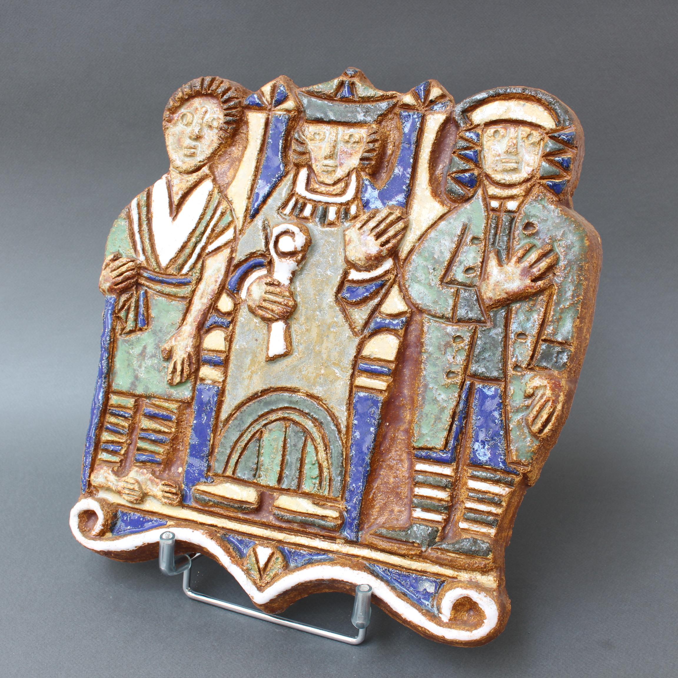 Plaque murale en céramique décorative française vintage avec trois personnages, par Les Argonautes, Vallauris, France (vers les années 1960). Une pièce rafraîchissante, naïve et charmante représentant trois hommes en robes et chapeaux d'antan. C'est