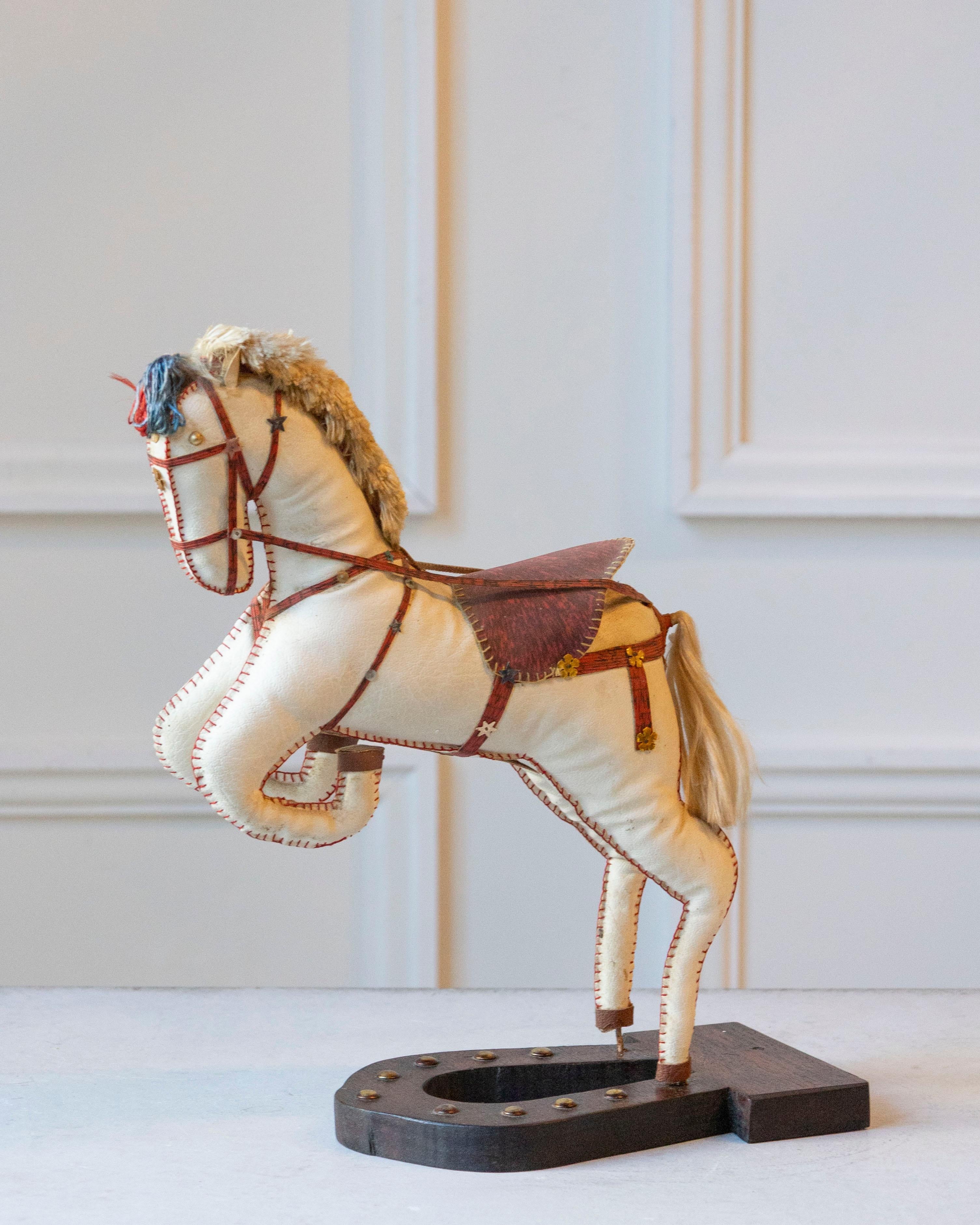 Charming and sculptural, this French decorative horse from the 20th century captures the elegance and vitality of equestrian form. Covered in soft moleskin, the figure rests on a black horseshoe-shaped wooden base and is poised in a rearing stance,