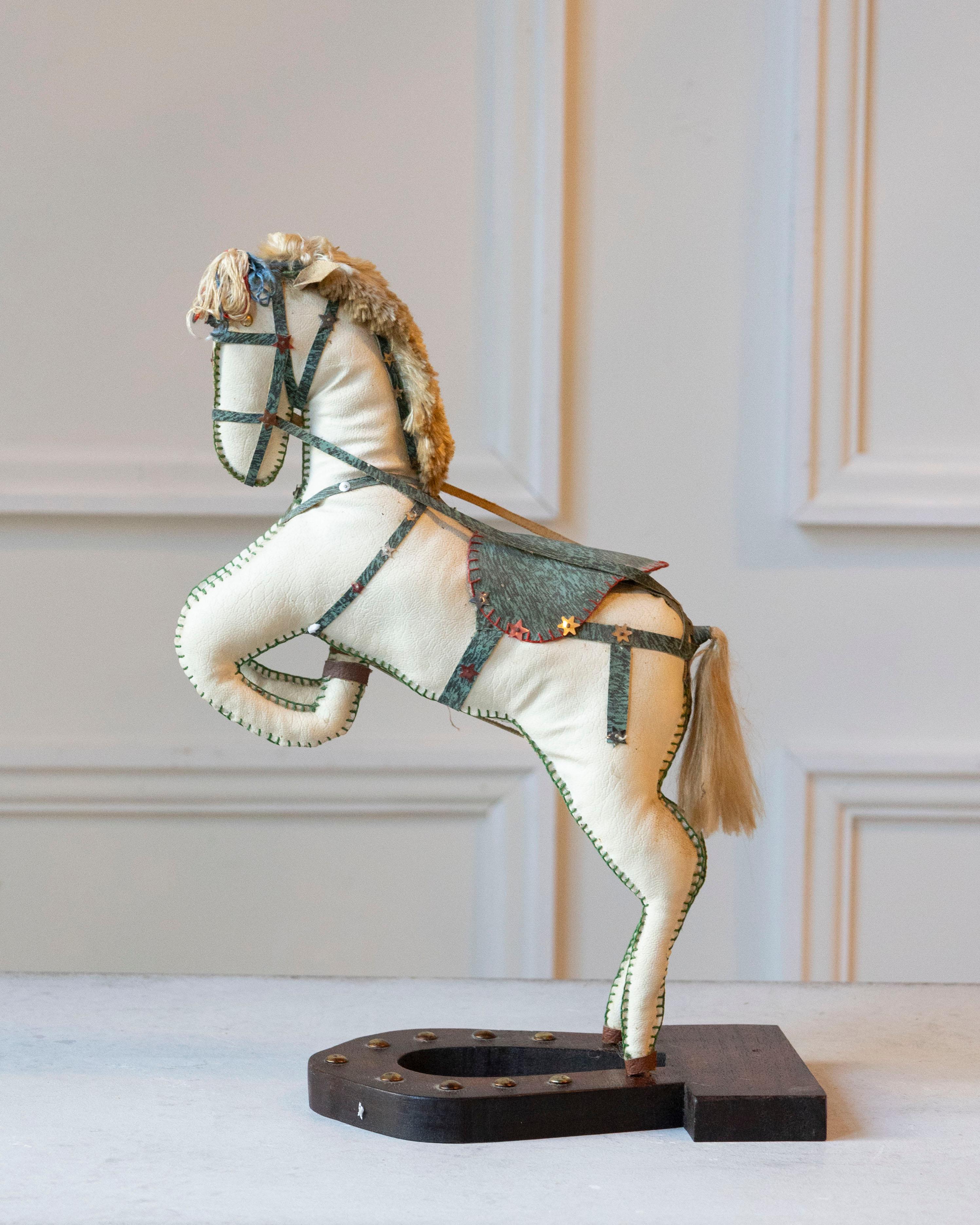 Charming and sculptural, this French decorative horse from the 20th century captures the elegance and vitality of equestrian form. Covered in soft moleskin, the figure rests on a black horseshoe-shaped wooden base and is poised in a rearing stance,