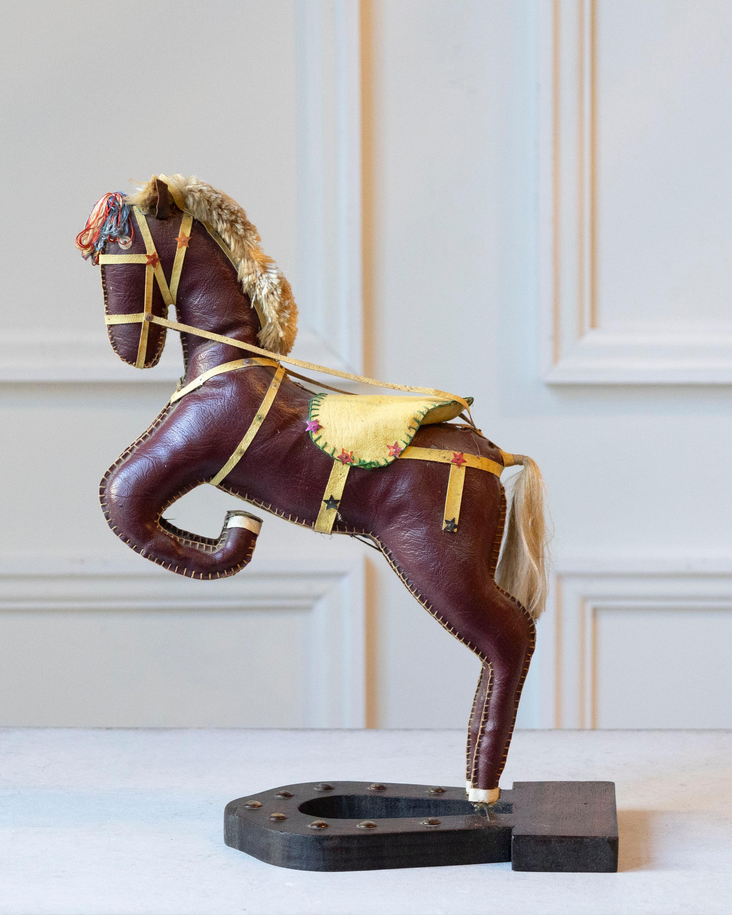 Charming and sculptural, this French decorative horse from the 20th century captures the elegance and vitality of equestrian form. Covered in soft moleskin, the figure rests on a black horseshoe-shaped wooden base and is poised in a rearing stance,