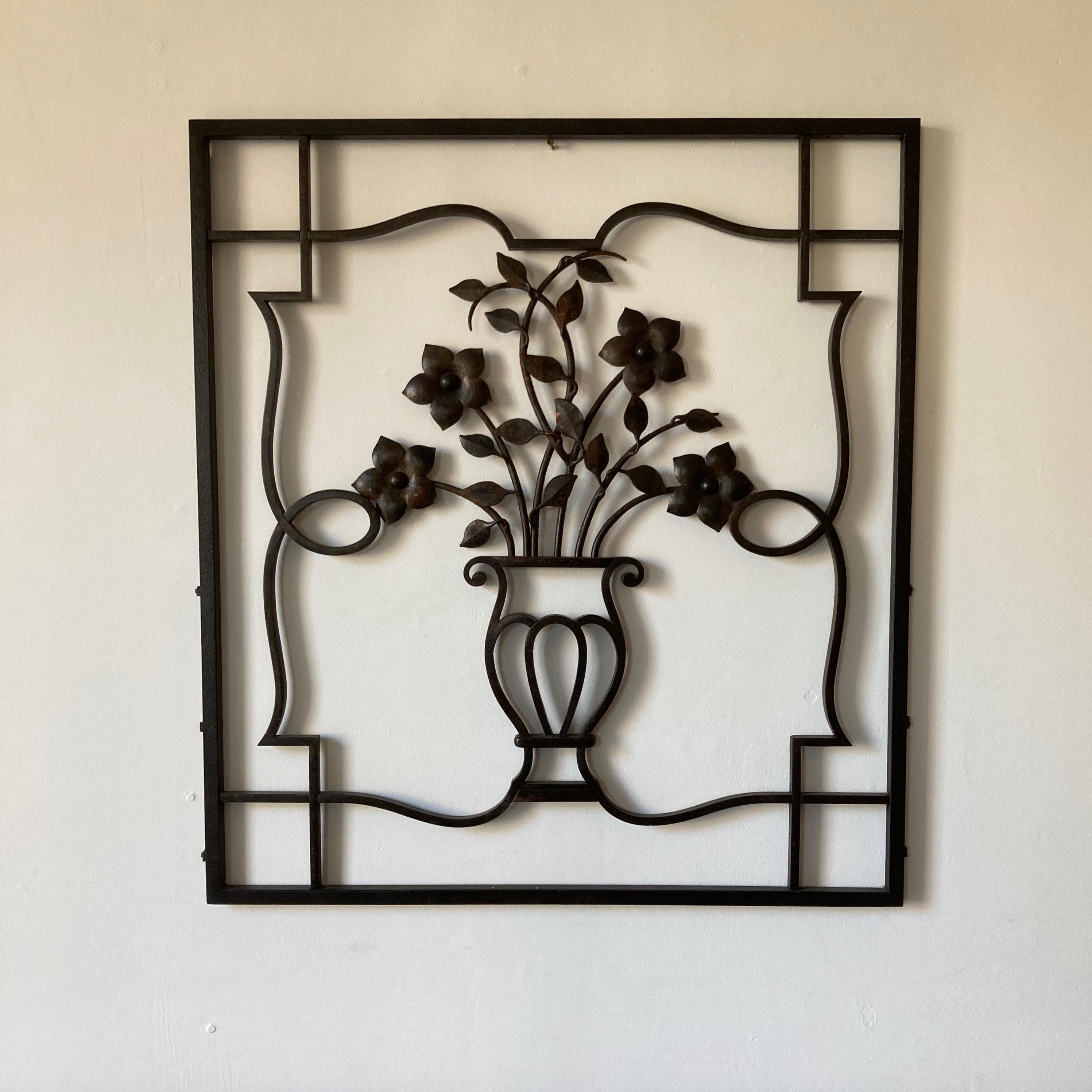 Decorative iron wall sculpture or applique, urn and floral motif. This wrought iron example of artisan craftsmanship. It makes a graphic, but soft statement.