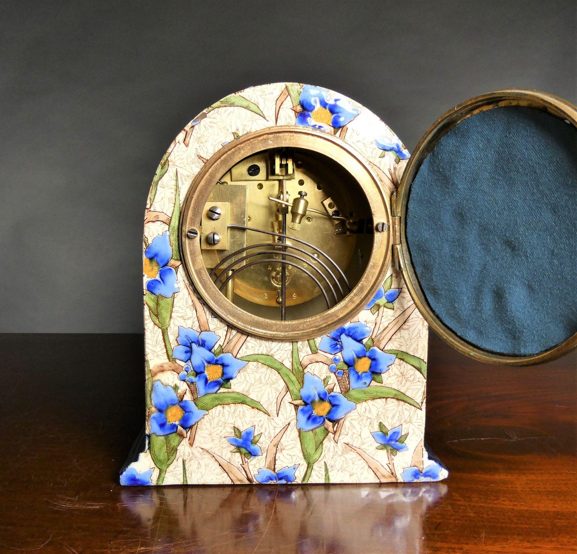 French Decorative Porcelain Clock Garniture
 
French mantel clock housed in an arch top porcelain case, beautifully decorated to all sides with flower applied relief resting on a  dark blue stepped plinth.
Gilded and chased bezel opening to the