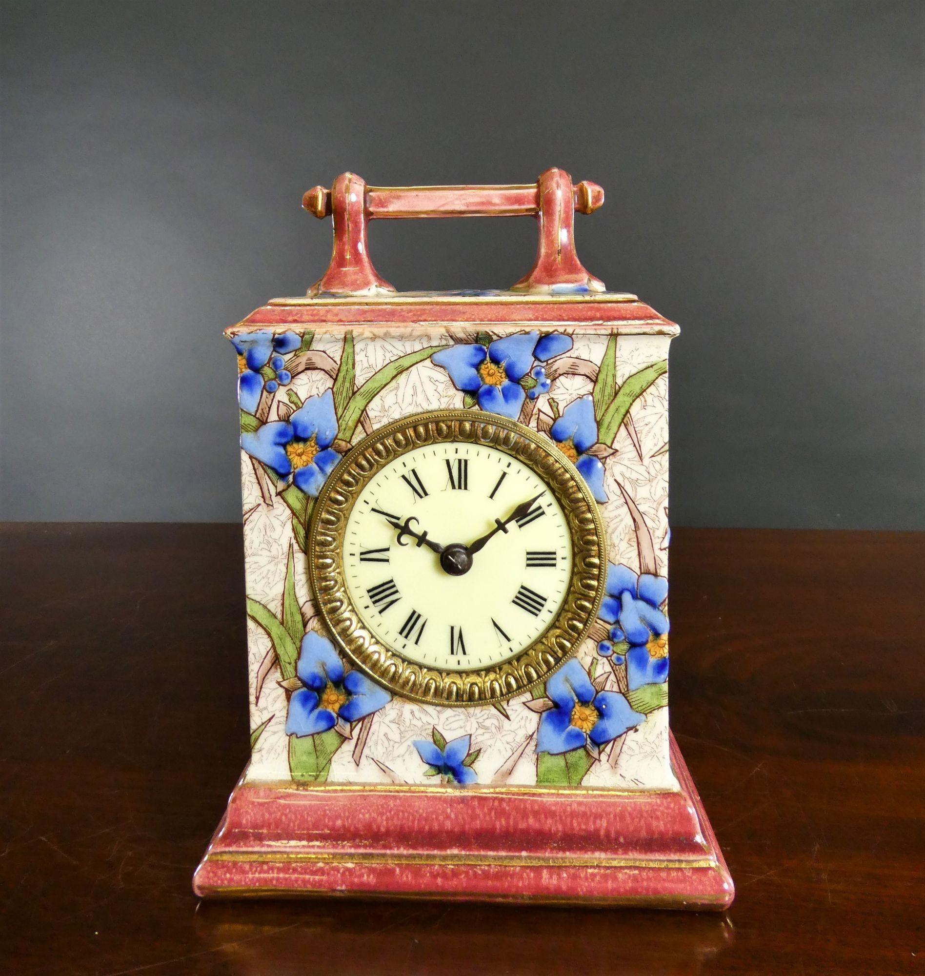 French decorative porcelain mantel clock housed in a square case surmounted by an ornate carrying handle.  Beautifully decorated to all sides with flower applied relief.
Ornate brass bezel, enamel dial with Roman numerals and minute markers and