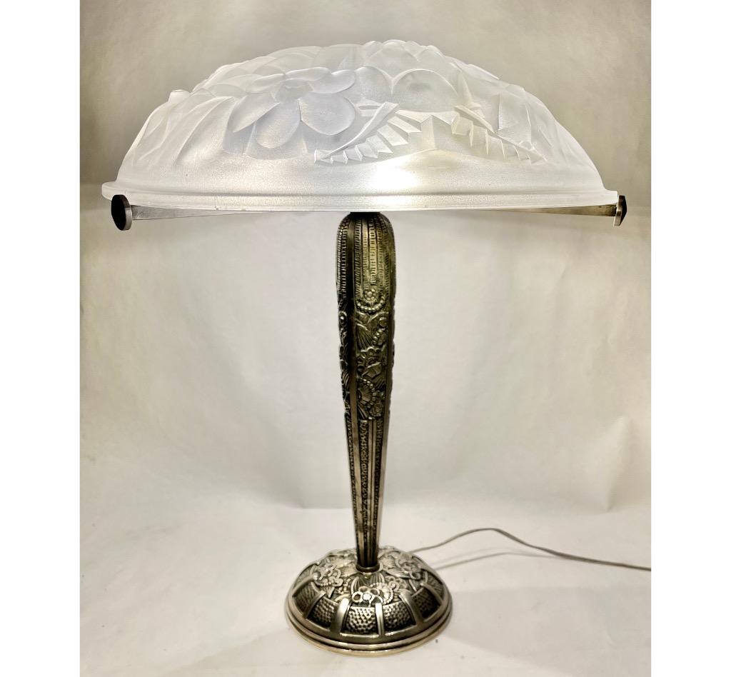 A wonderful French 1930 art deco table lamp made by the Paris based company of Léon Hugue, A nickel plated solid brass or bronze base holds a signed dome shaped shade by Degué. Done in clear frosted moulded-pressed glass.
Léon Hugue was a producer