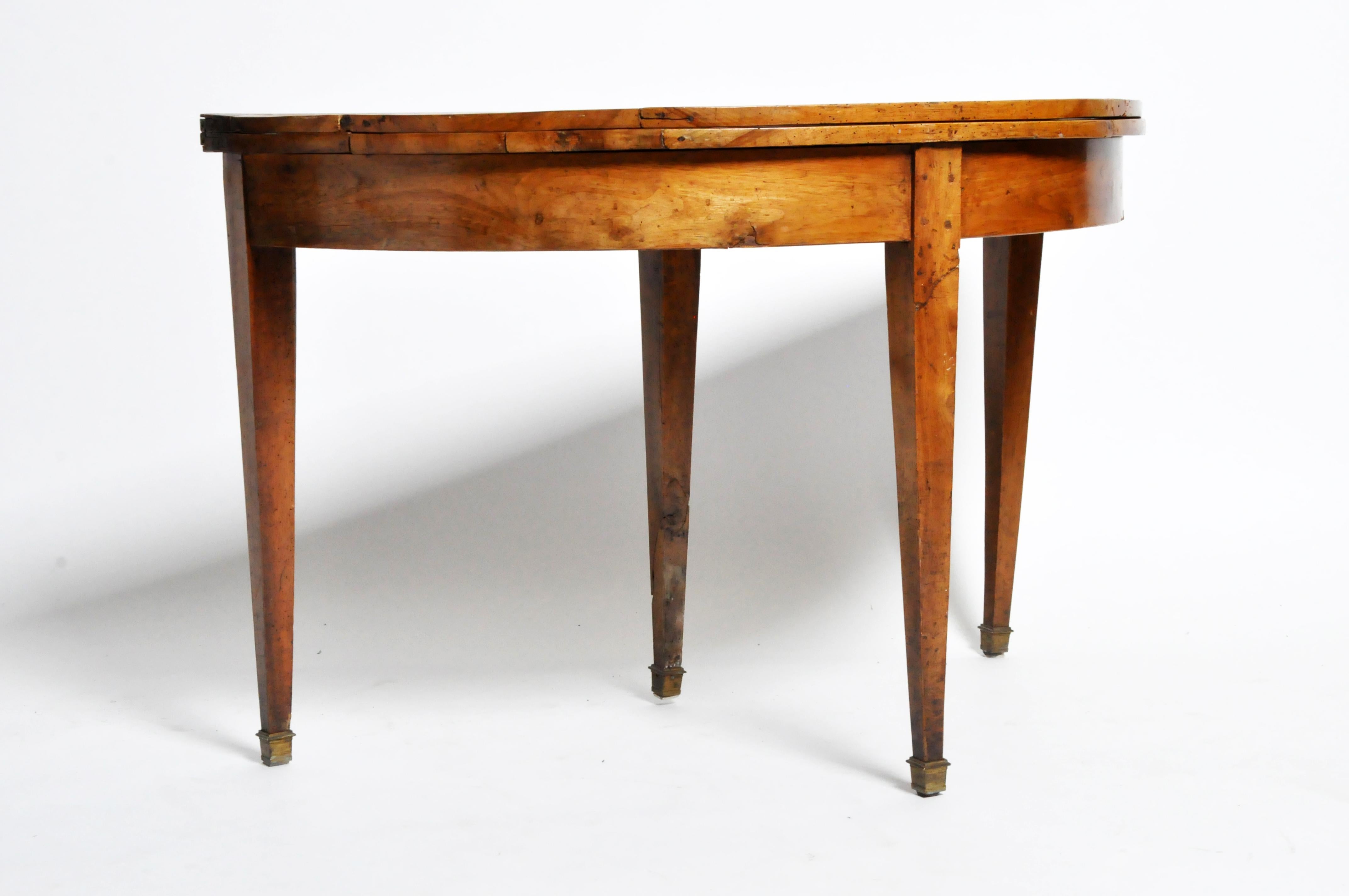 This demilune folding game table is from France and dates to the 19th century, circa 1850. The table opens up to form a circular table to seat additional people, probably for playing cards. The table is unusually simple, with the only explicit