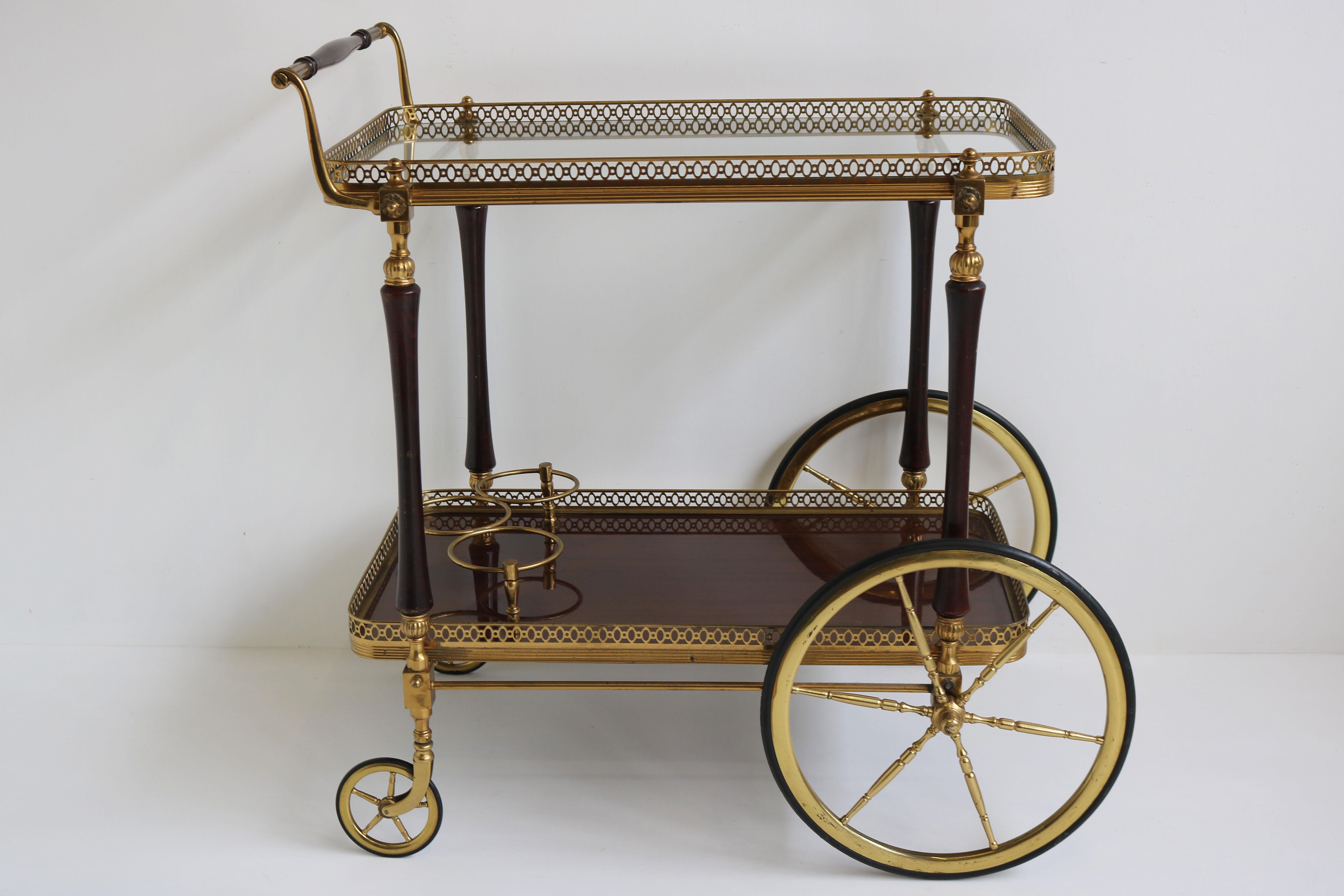 Exquisite luxury bar cart / serving trolley designed by Maison Bagues 1950 in France. 
The combination between the brass, glass & mahogany is marvelous. 
The bar cart has a glass top, and mahogany shelf with 3 brass bottle holders. 
Amazing
