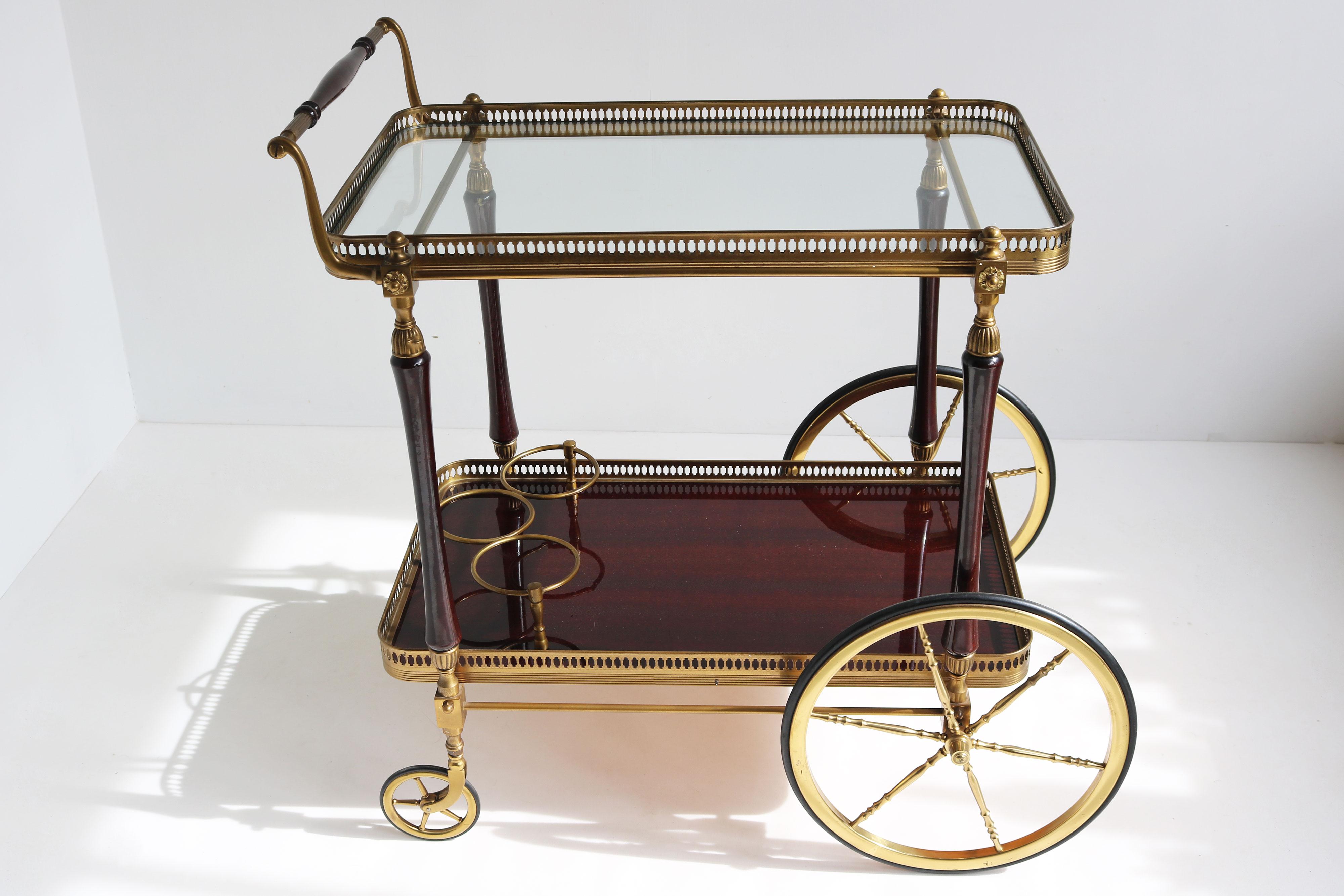 Exquisite luxury bar cart / serving trolley designed by Maison Bagues 1950 in France.The combination between the brass , glass & mahogany is marvelous.  
The bar cart has a glass top , and mahogany shelf with 3 brass bottle holders. Amazing