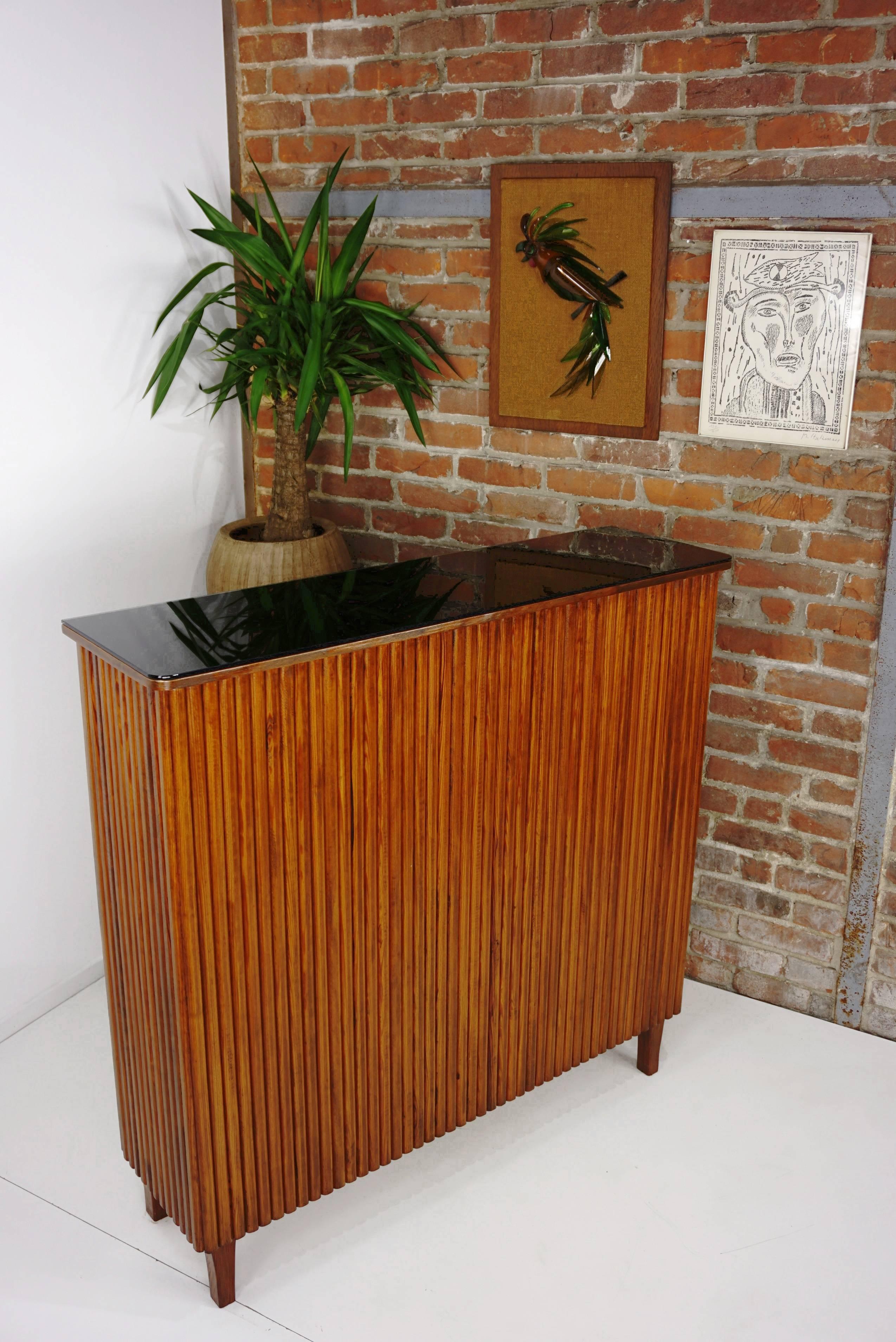 Beautifully crafted, fine and delicate French work for this 1960s bar all in solid wood, dressed in black faux - leather and the interior walls are decorated with mirrors. The tray is a black glass. Long and shallow (113 cm / 33 cm), it is in