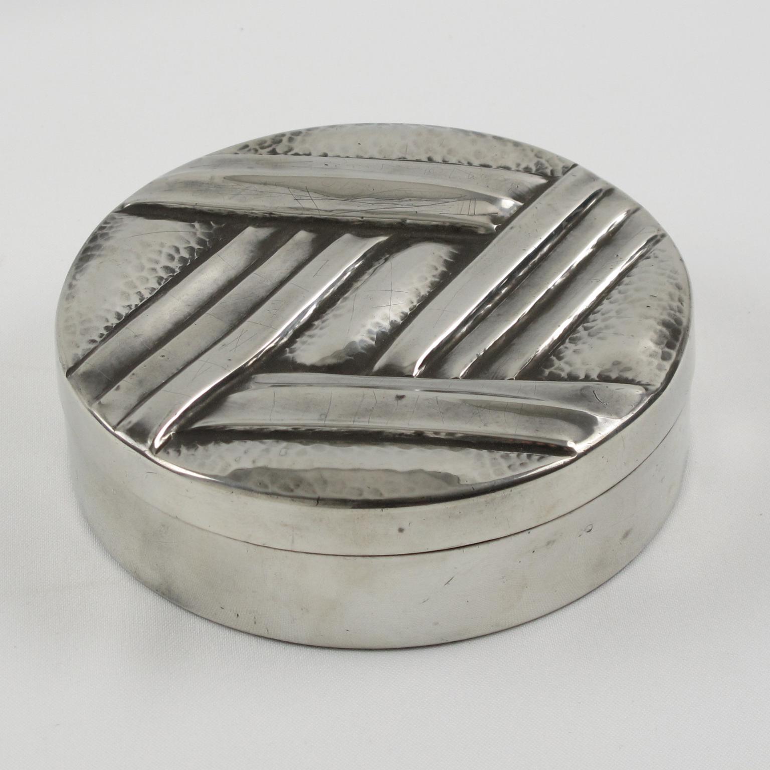 Elegant French Art Deco polished pewter decorative box by L. Guilbaud. Perfect for vanity or boudoir or any modern Art Deco interior. Round lidded shape with carved and embossed typical Art Deco geometric design, signed 'L. Guilbaud' underside.
