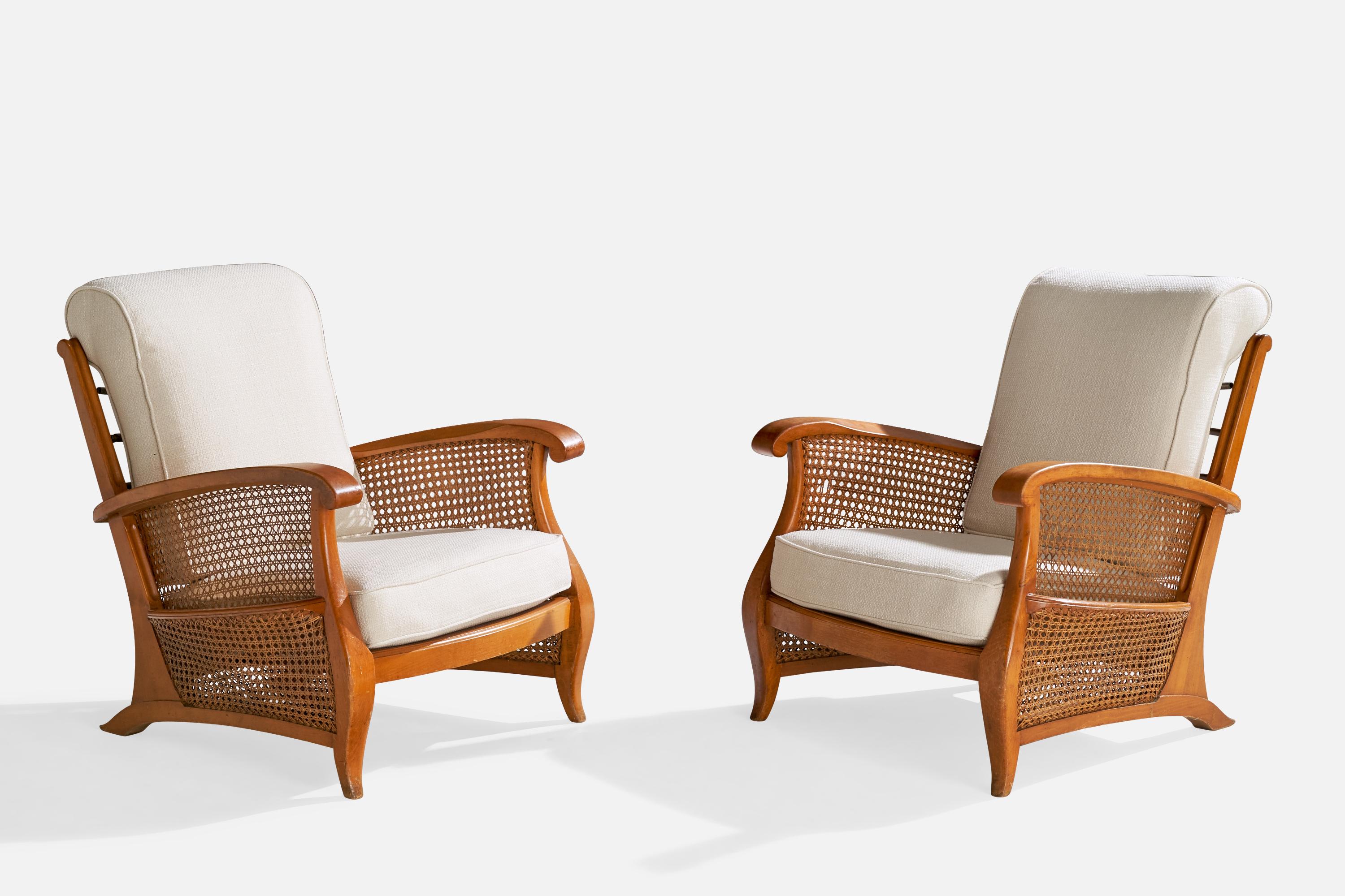A pair of oak, cane, metal and white fabric lounge chairs with magazine racks designed and produced in France, c. 1940s.

Seat height: 15“

All upholstered furniture can be reupholstered upon request for an additional fee. Lead times will be an